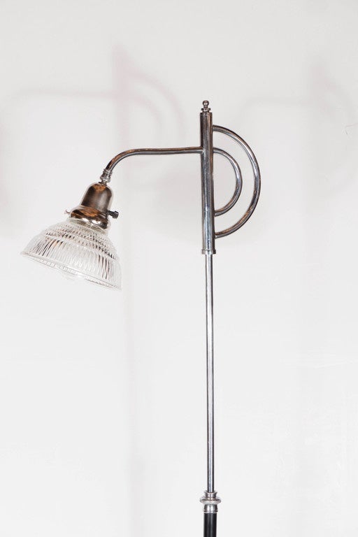 Art Deco Machine Age floor lamp in chrome with black enamel and a ribbed glass shade.  This Art Deco floor lamp has a black enamel circular base with an inset chrome band and centerpiece that gives it a stepped Skyscraper design.  This base holds