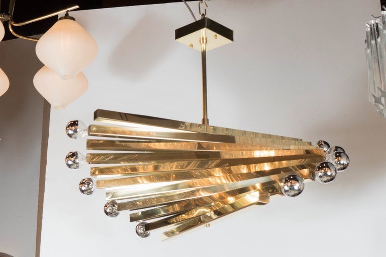 This sculptural Mid-Century Modernist Gaetano Sciolari chandelier features a spiral design consisting of 11 rods with alternating bulb fittings at one end of each rod. The sweeping spiral design coupled with the polished brass finish and half