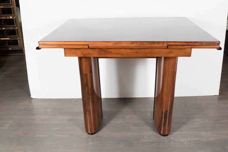 An elegant Art Deco dining table black lacquer and exotic walnut inlay with two extension leaves and rounded column supports. This table features an exquisite array of exotic woods. The main body of the table is of Mahogany, as well as the two
