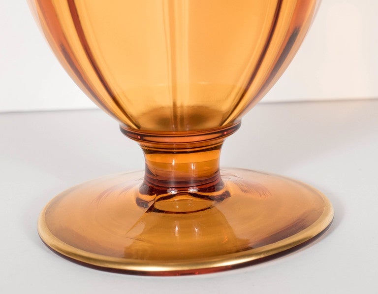 This very elegant covered bowl features a gorgeous amber glass in a stylized neoclassic etruscan form design.It features 24k yellow gold banding in relief form with also concentric gold band detailing. This piece would be a great accessory with any