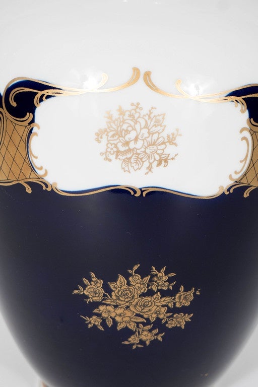 Neoclassical Revival style Porcelain vase in White and Cobalt Blue with 24K Gold overlay accents.  This beautiful porcelain vase is in a classic shape with a Cobalt Blue base and white top section that is divided with a 24K Gold scroll design