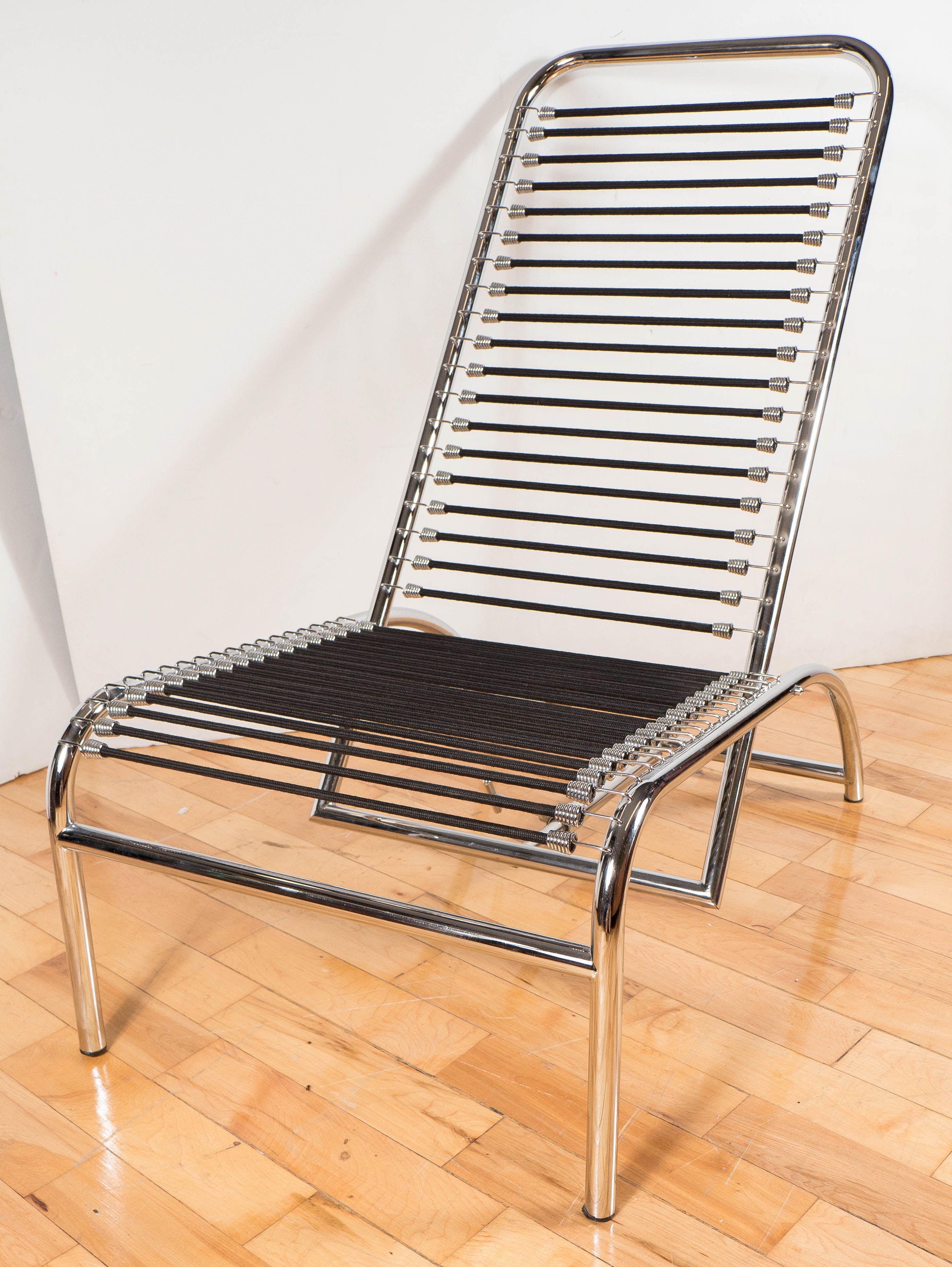 Original Sandows tubular lounge or easy chair by Rene Herbst. A tubular polished aluminum frame and adjustable back, with horizontal attached black bands which serve as supports for both seat and back. This easy chair was originally designed by Rene