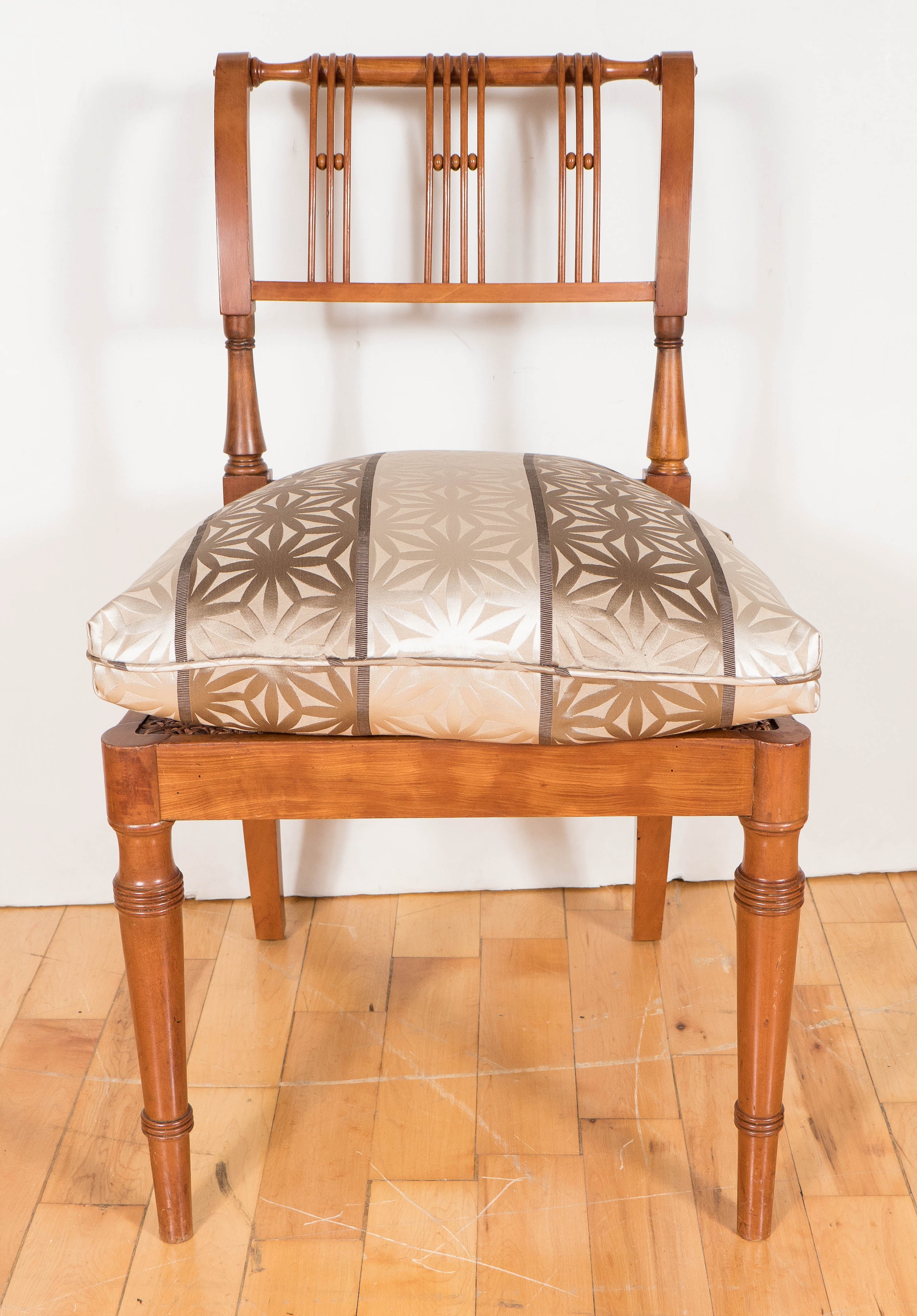 This Biedermeier chair was realized in cherrywood with a very comfortable seat cushion attractively decorated in a geometric design in cream and topaz silk patterns The backrest is curved with a tilted shoulder and ends in a volute -shaped scroll,