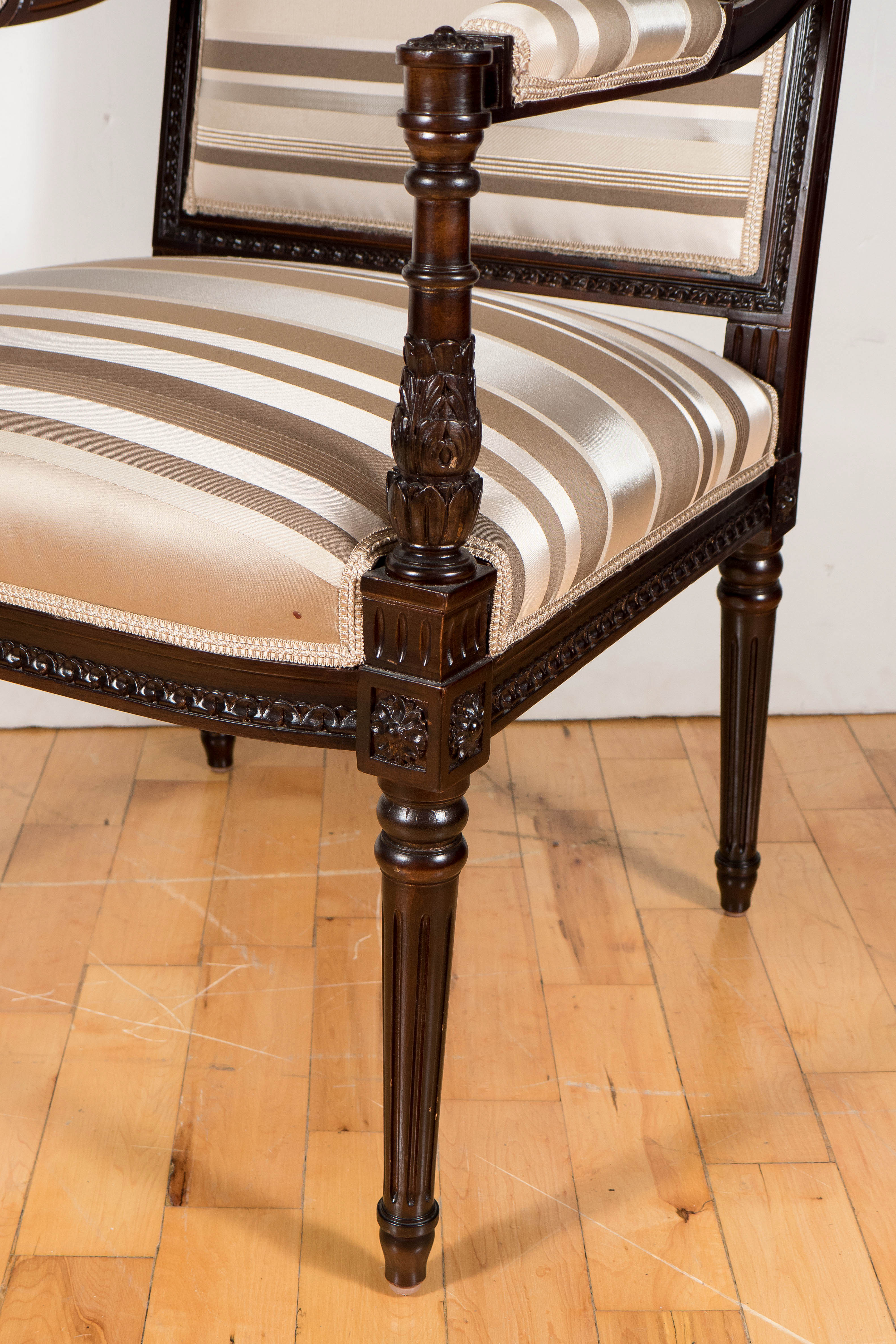 This handsome Hollywood Regency occasional chair was realized in the United States, circa 1945. It features an intricately embellished frame in ebonized mahogany with tapered balustrade style legs. The back and seat offer fine hand-carved beading