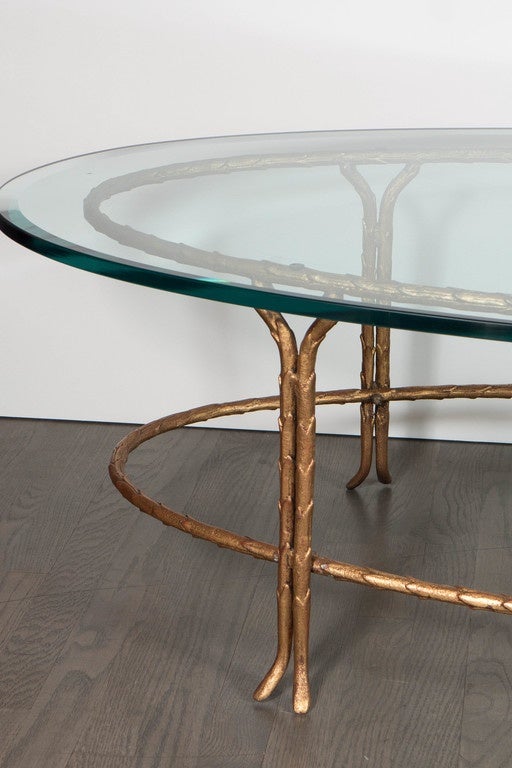 This elegant Bagues gilt bronze cocktail table features an oval frame in a stylized foliage design in a naturalistic form with vertical supports in tapered form with a serpentine form. The table consists of two oval frames with a ¾