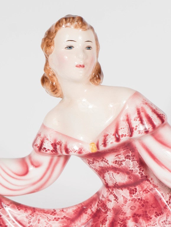 This ceramic figurine of an elegant woman portrayed in a hand-painted lace front gown in Rose coloring with white and cream backgrounds is named 'Jolanthe.' Her gown has a lace overlay with sleeves of cream / white with highlights of rose. She is