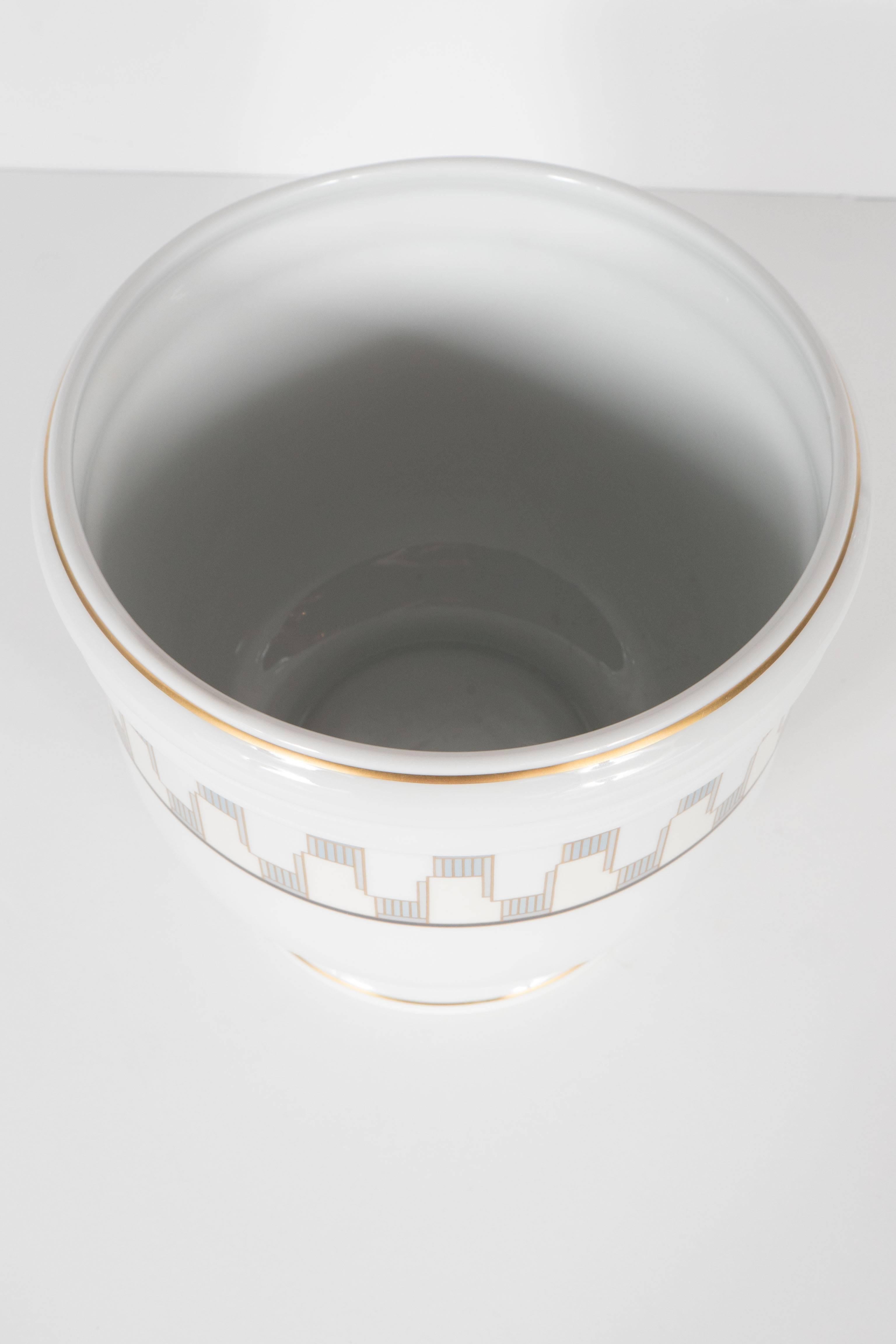 Fabricated from lustrous Limoges china, this gorgeous cachepot features an Art Deco cubist geometric pattern in hues of pale citrine, creme and pale grey. The lip and the base are accented with rings of 24-karat yellow gold gilt. It bears the mark
