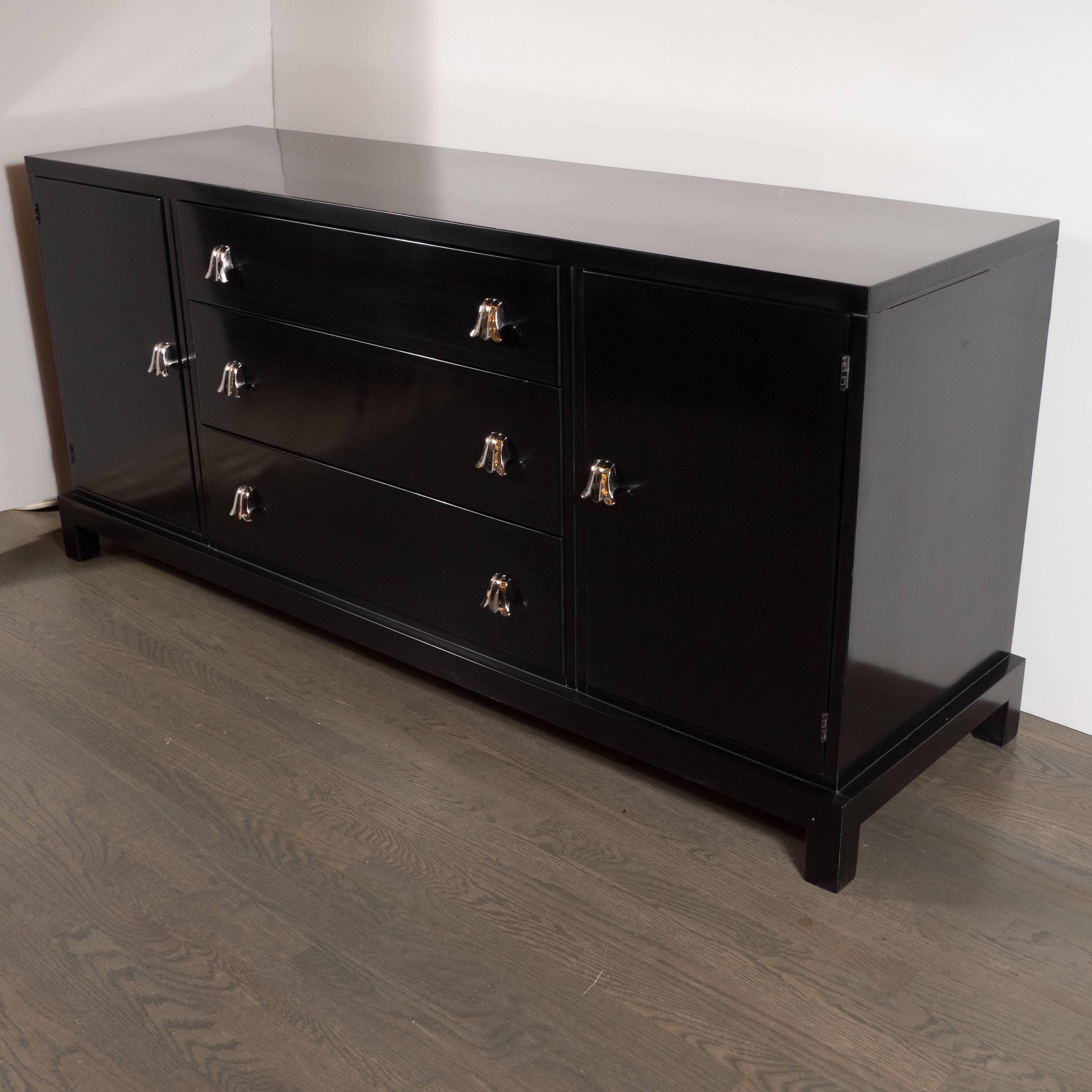 This elegant skyscraper style sideboard or credenza was fabricated circa 1945 by the esteemed American maker Grosfeld House. It features an ebonized walnut body; square legs; and nickel stylized tulip pulls. There are three spacious drawers in the