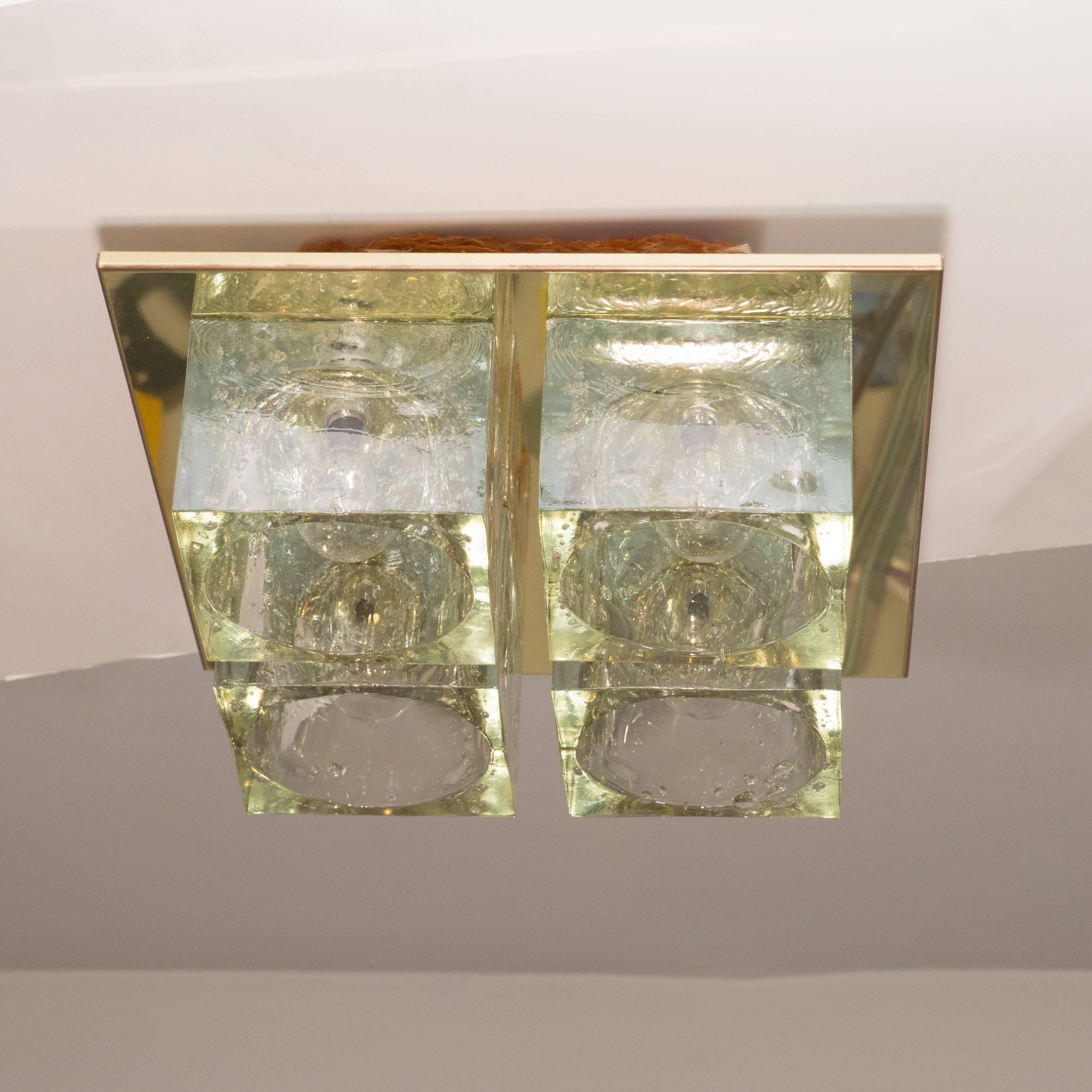 This brilliant Mid-Century Modern flush mount chandelier was realized by the esteemed Italian glass studio Sciolari, circa 1970. It features four thick translucent glass cubed shades with inset bulbs attached to a close fitting brass backplate. This