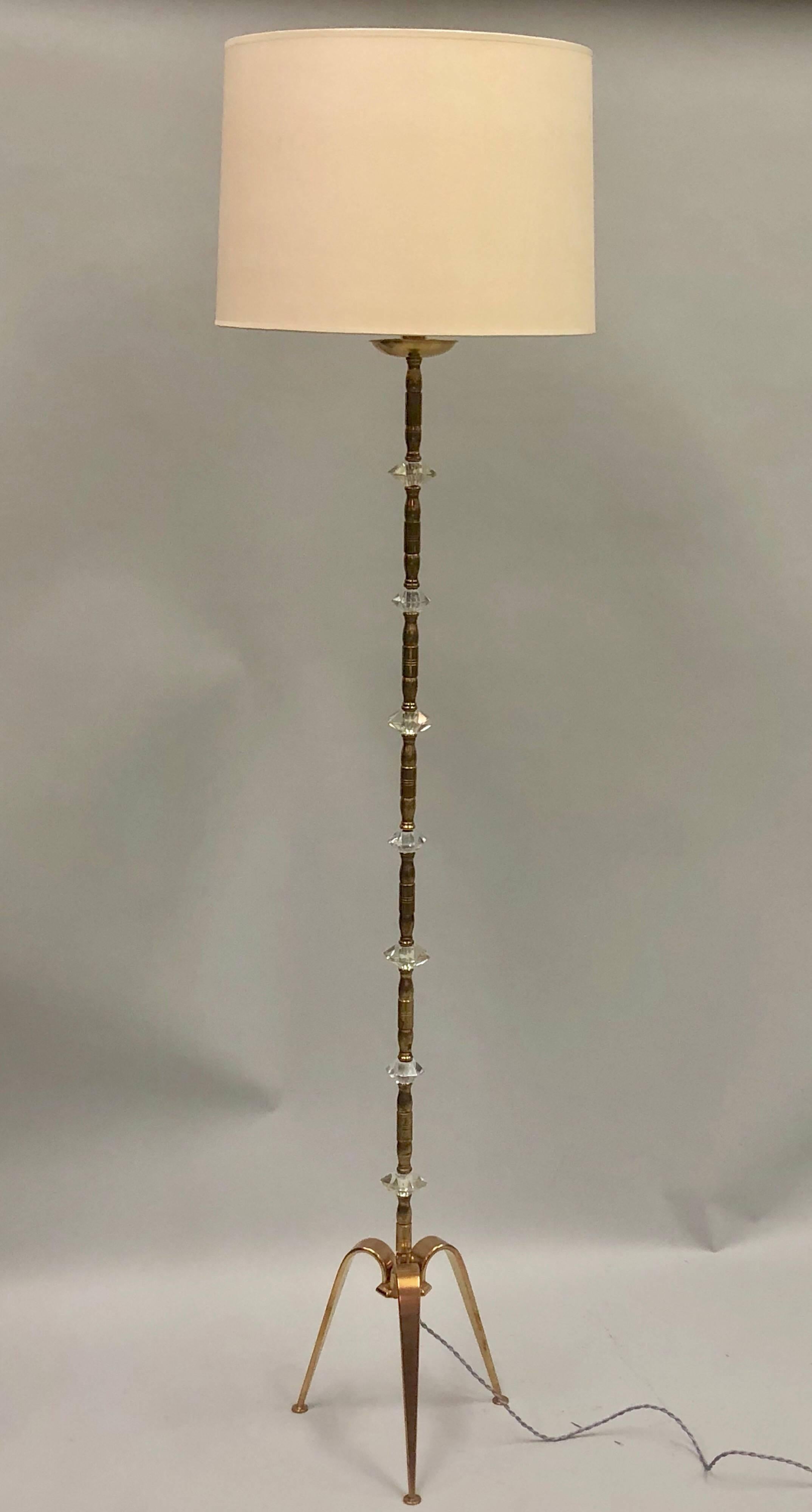 Pair of French Mid-Century Modern neoclassical brass and crystal floor lamps by Maison Jansen for Maison Baguès. 

Elegant standing lamps with tapered legs forming a tripod and pieces of cut crystal interspersed along the delicate brass stems.