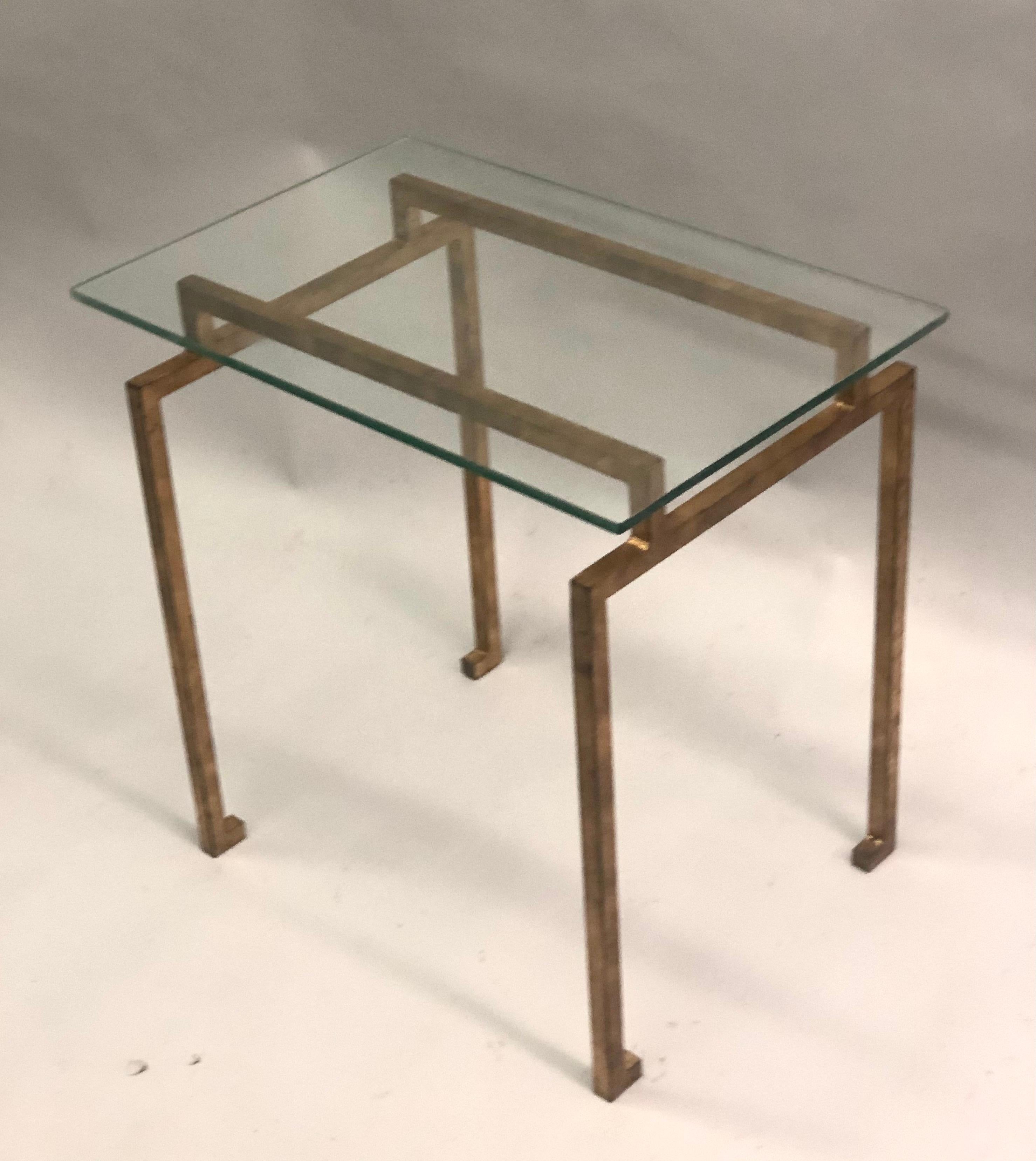 Une paire de tables d'appoint ou de bout de style midcentury français dans l'esprit néoclassique moderne. Les tables sont en fer forgé doré avec de délicats sabots tournés dans le goût égyptien. 

Littérature : Paire similaire vendue chez