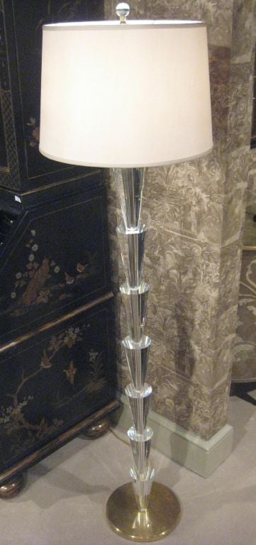 Two sober and elegant Italian midcentury style solid crystal standing lamps in the Modern neoclassical spirit with each piece of crystal delicately cut to reflect light, tapered and arranged sequentially on top of each other and resting on brass