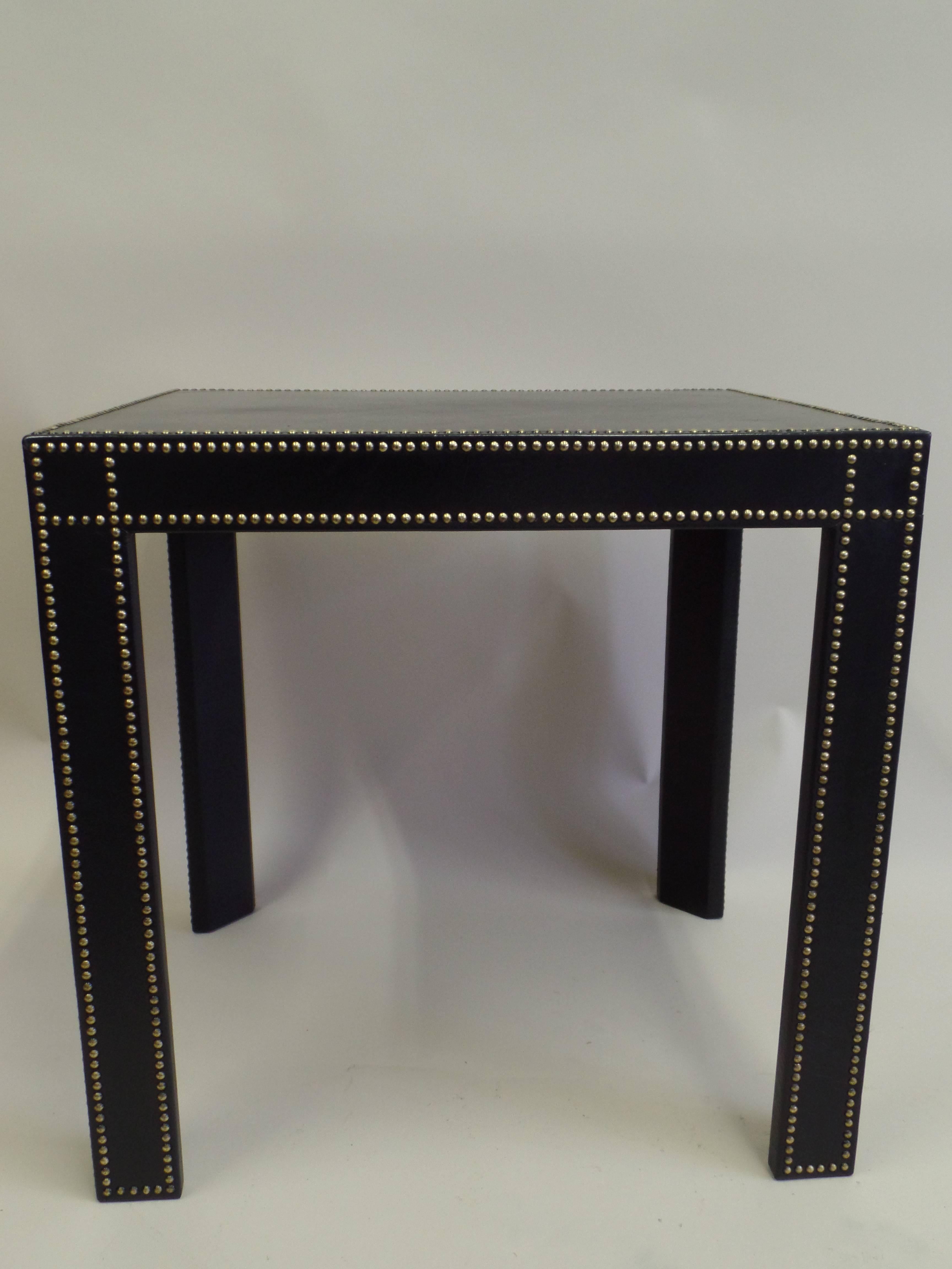An elegant pair of French Mid-Century Modern Neoclassical style black leather studded side tables / nightstands attributed to the French artist, Pierre Lottier. The tables are rectangular and present serene, minimalist forms and lines. They have