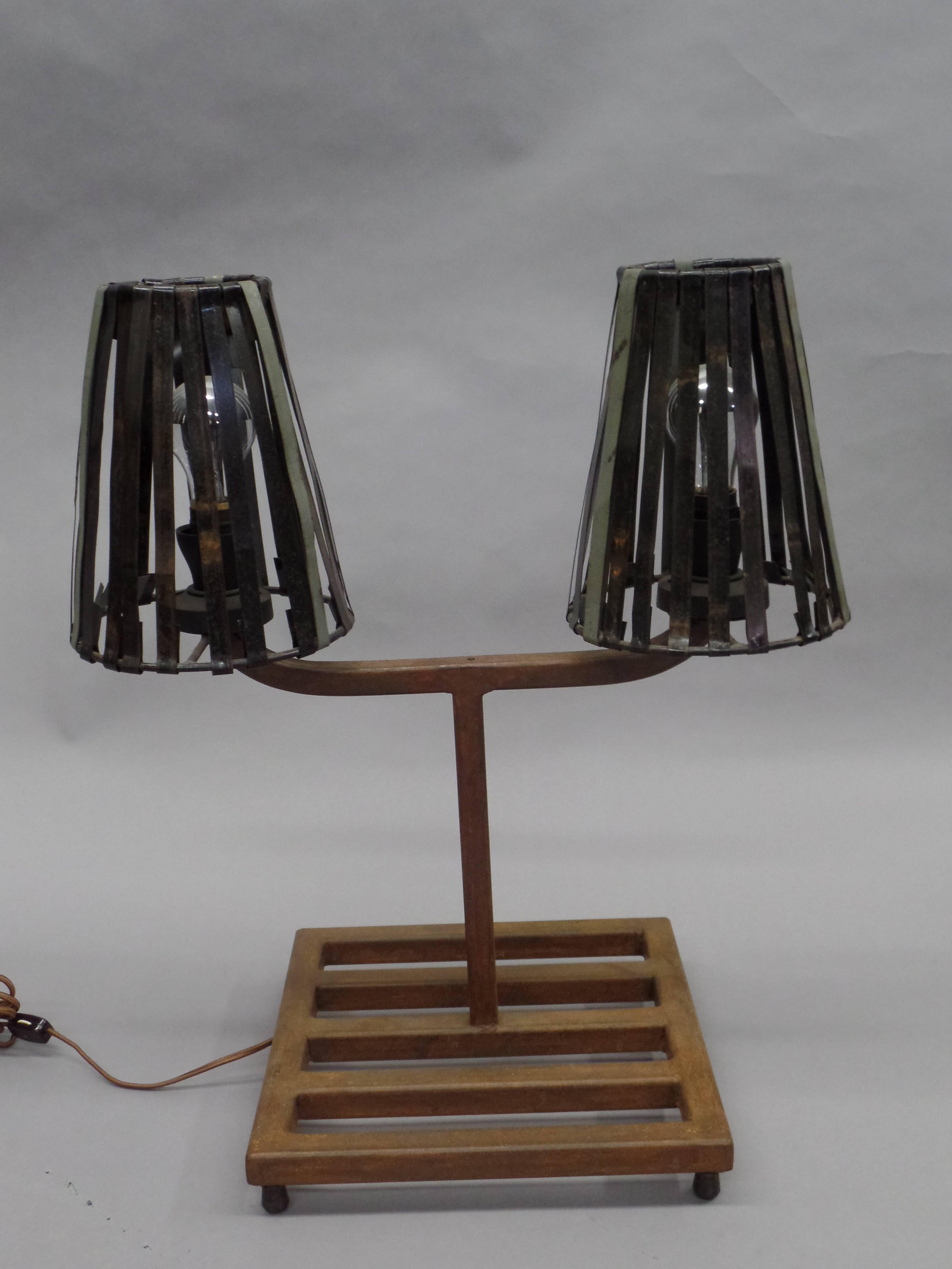 An original and stunning pair of French Mid-Century Modern table lamps in the style of Jean Prouvé. The pieces have a distinctive Industrial Design style consistent with Prouvé and are composed of patinated steel grill bases which support Y-form