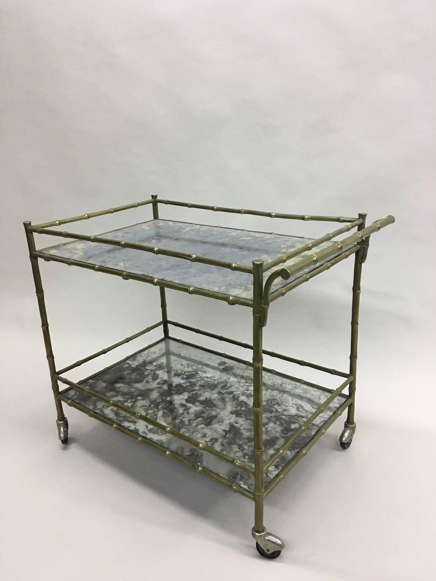 An elegant French midcentury solid brass / bronze faux bamboo tea cart / bar cart with mercury glass mirrored tops by Maison Baguès embracing modern and neoclassical traditions. The piece has fine details and a solid feel.