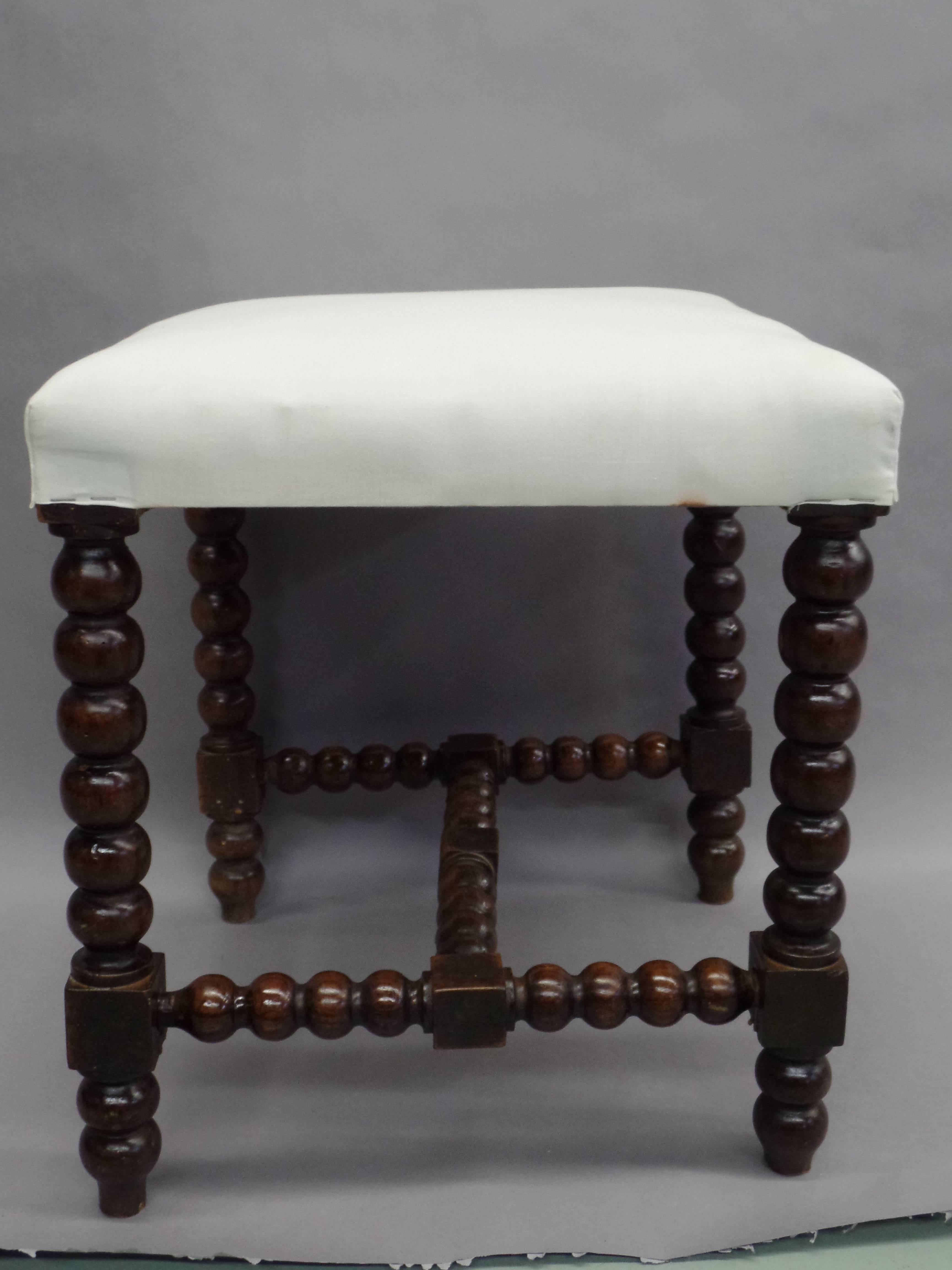 An elegant, sober pair of French Modern Neoclassical Louis XIII style hand-carved wood benches or stools with the legs and stretchers formed by successive stacked ball forms.