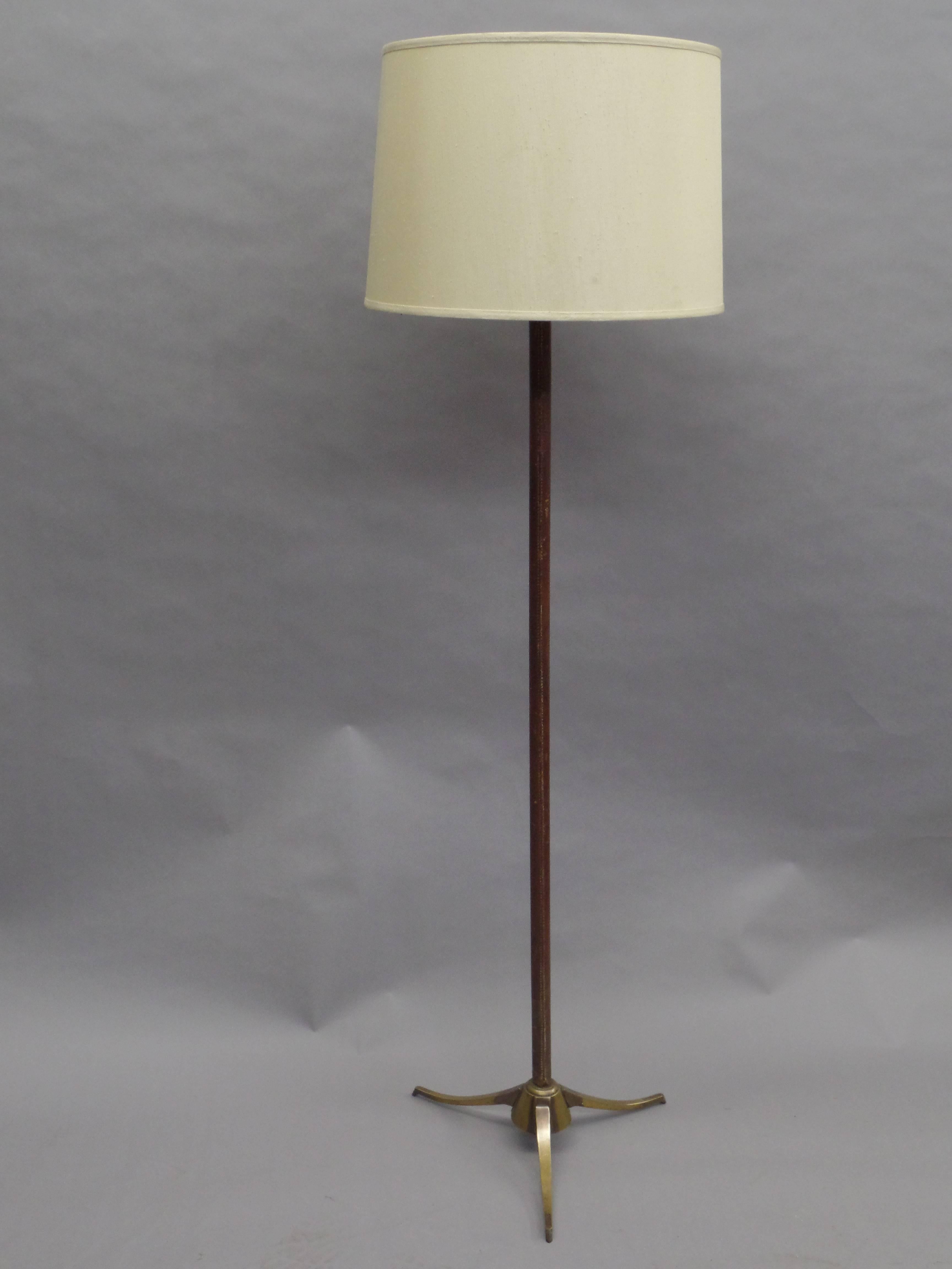 Elegant French Mid-Century Modern neoclassical handstitched leather standing lamp in the style of Jacques Adnet.

The tripod base is in solid brass and reflects French Art Deco, modern and neoclassical influences. Leather is delicately