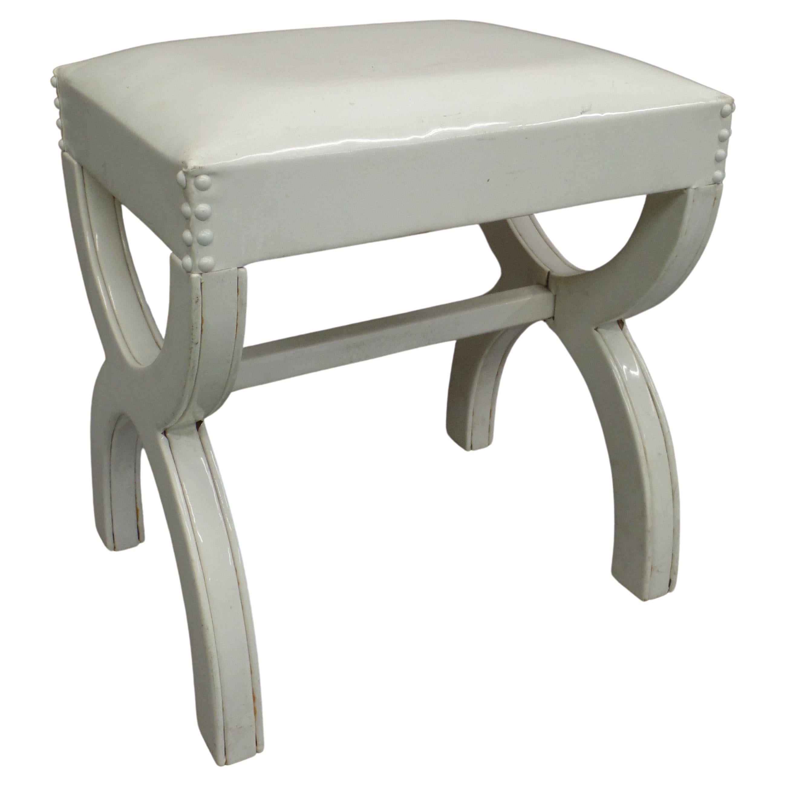 An Elegant French Midcentury Bench or Stool in the Modern Neoclassical Style with an X-frame structure. The The stool is original in its total white composition and the use of white vinyl simulated leather elevates it to a unique luxury status. The