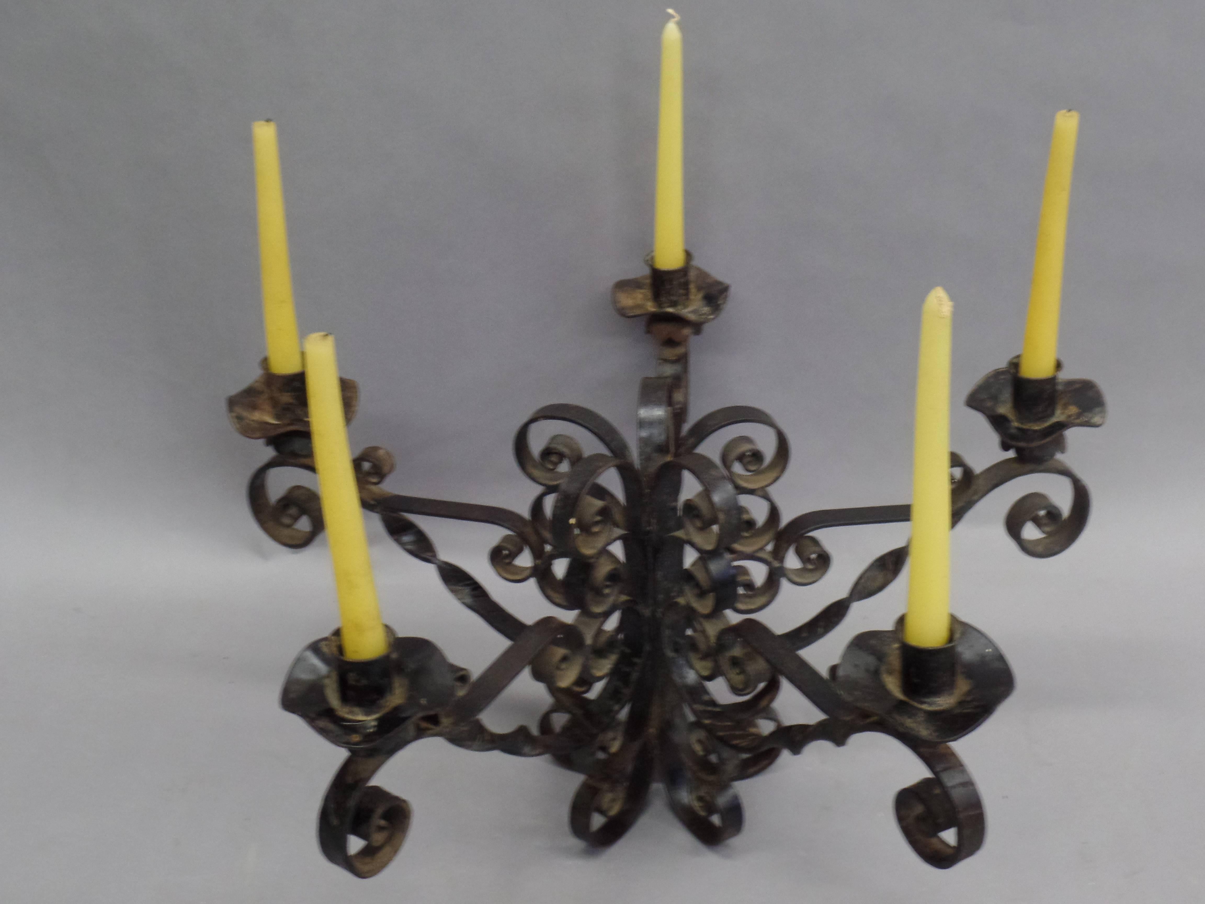 French midcentury candelabra in handwrought iron in the form of twisting volutes. Five arms.

Can be used with candles or electrified, can be used as a table lamp, center piece or hung as a chandelier. 

Height with candles shown is 18