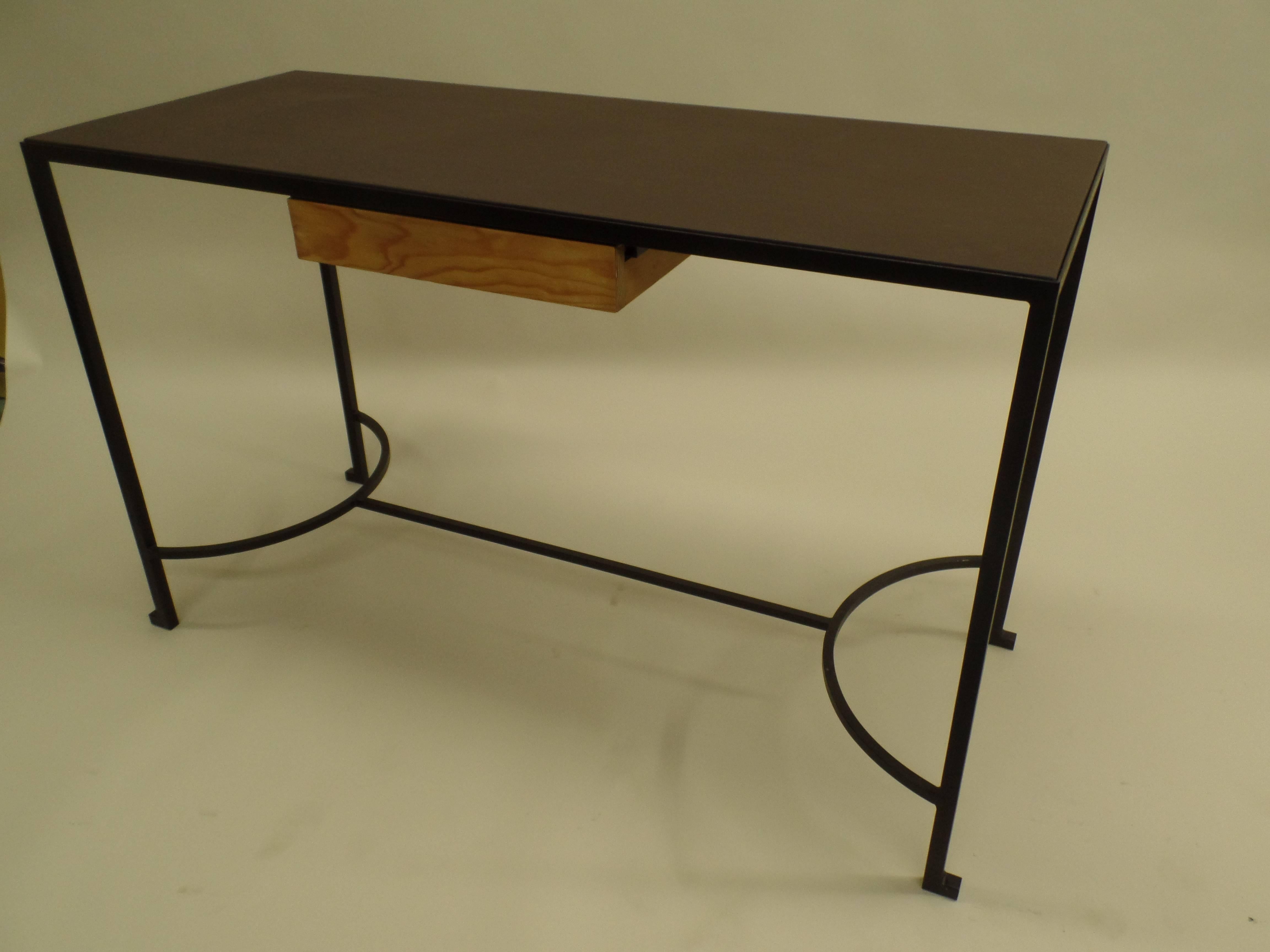 French Mid-Century console / desk attributed to Marc du Plantier in the modern neoclassical taste.

The piece is composed of hand wrought iron legs and base with an inset leather top and one wood pencil drawer. The delicate legs are united by a