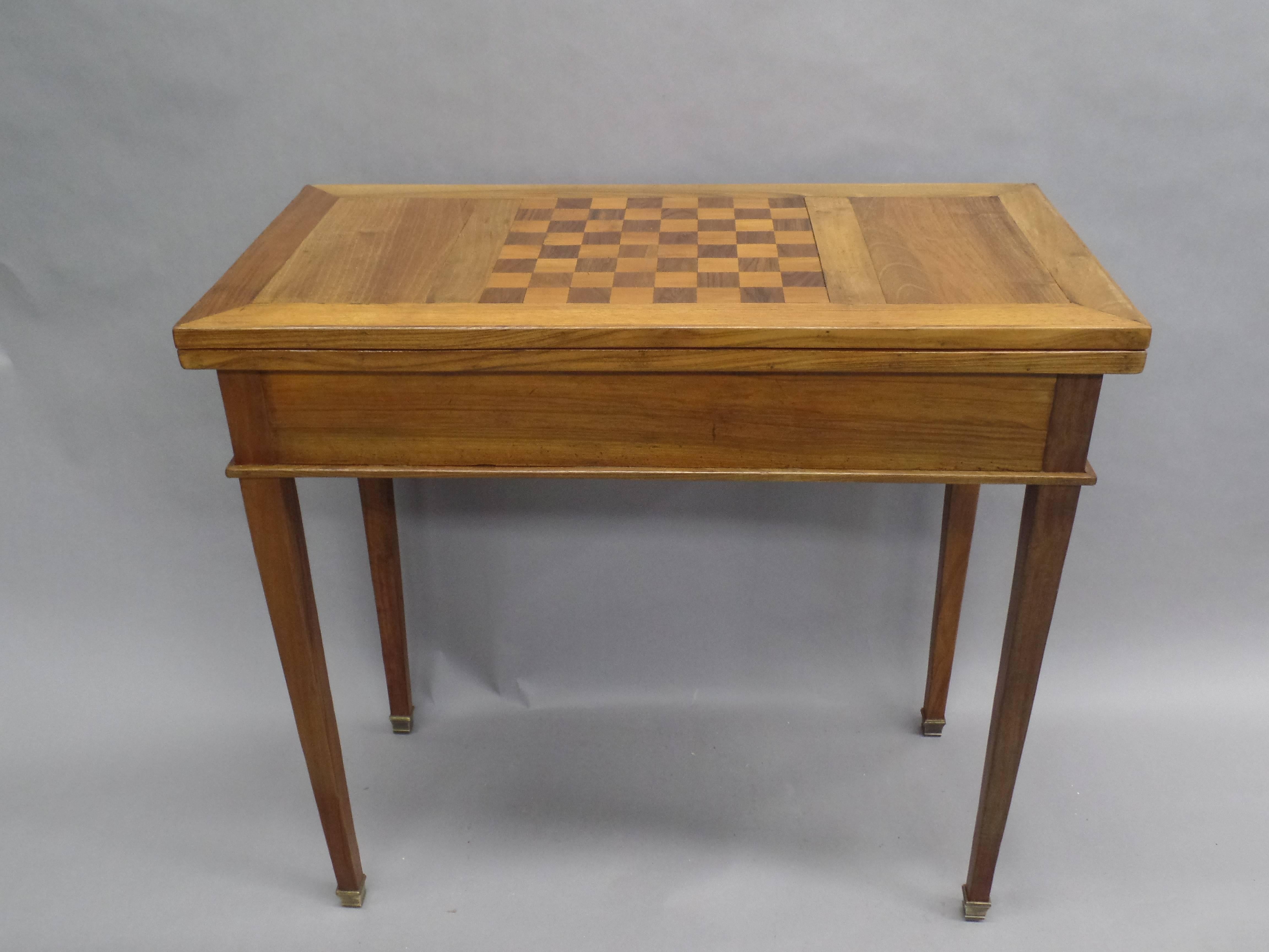 A distinguished French  Mid-Century Modern Neoclassical table in the Style of Louis XVI by Maison Jansen from the Midcentury featuring a parquetry top made for chess and flip top made for playing cards. Tapered legs with bronze sabots extend to