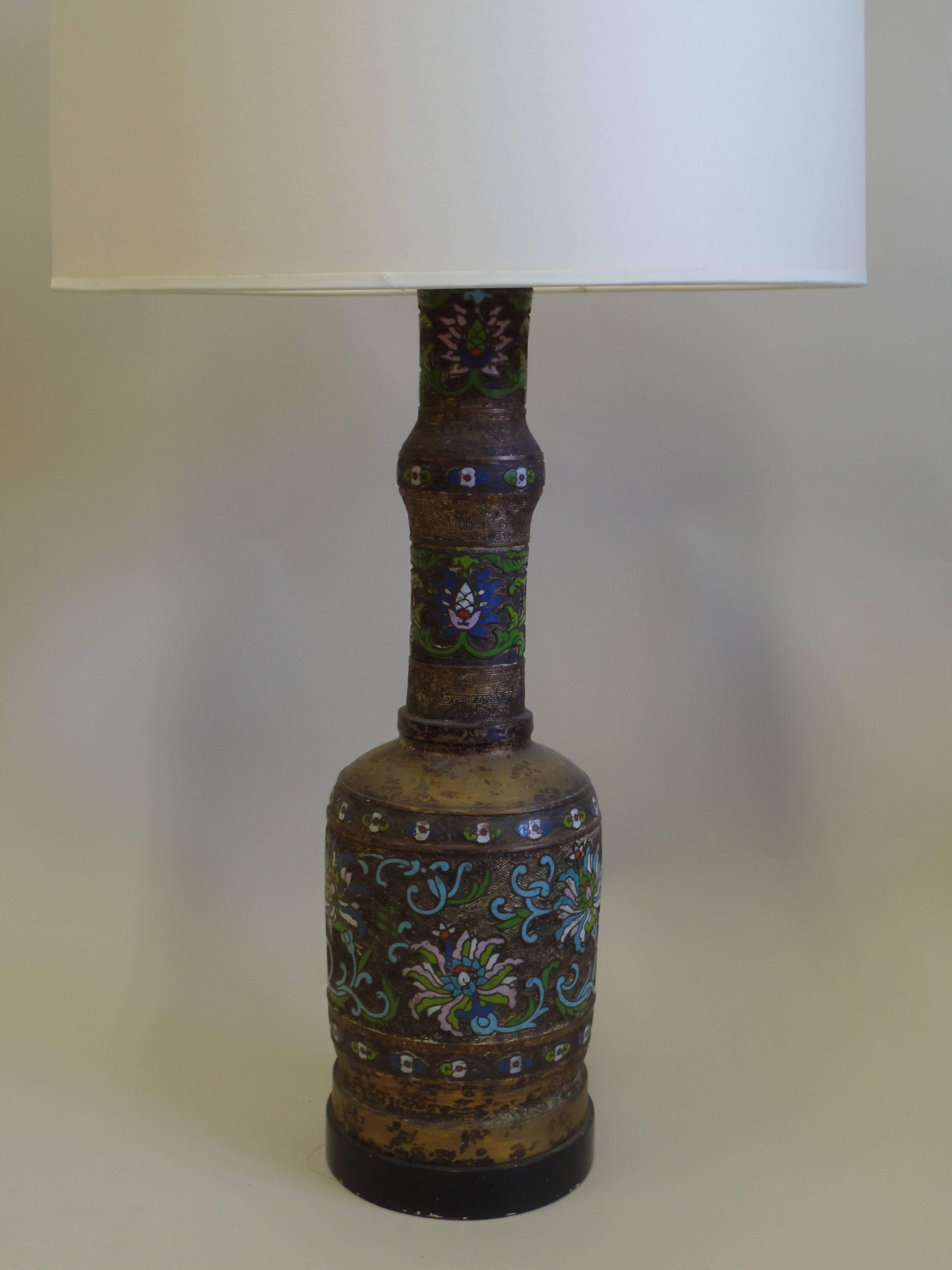 A large pair of gilt bronze and hand-painted and enameled Champleve lamps.
An elegant modern neoclassical urn form is combined with a mottled gilt bronze surface and with enamel inlaid (Cloisonne) multicolored florals around the body and neck