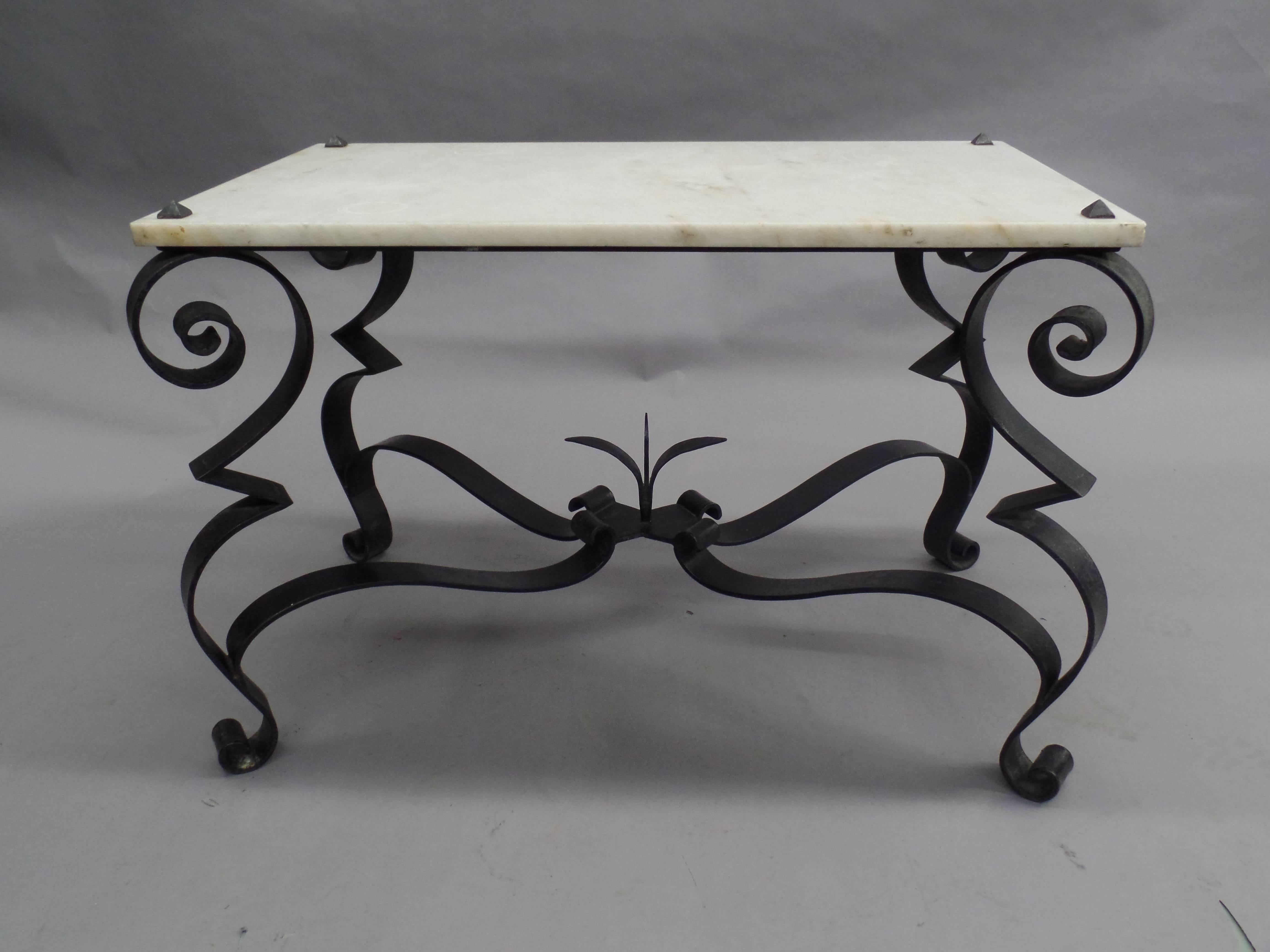 A Classic French Mid-century hand wrought iron coffee table / side or end table in the Modern Neo-Baroque style with a white marble top. The hand wrought iron is curved and spiraling at the foot and base of each leg; each leg is united by stretchers