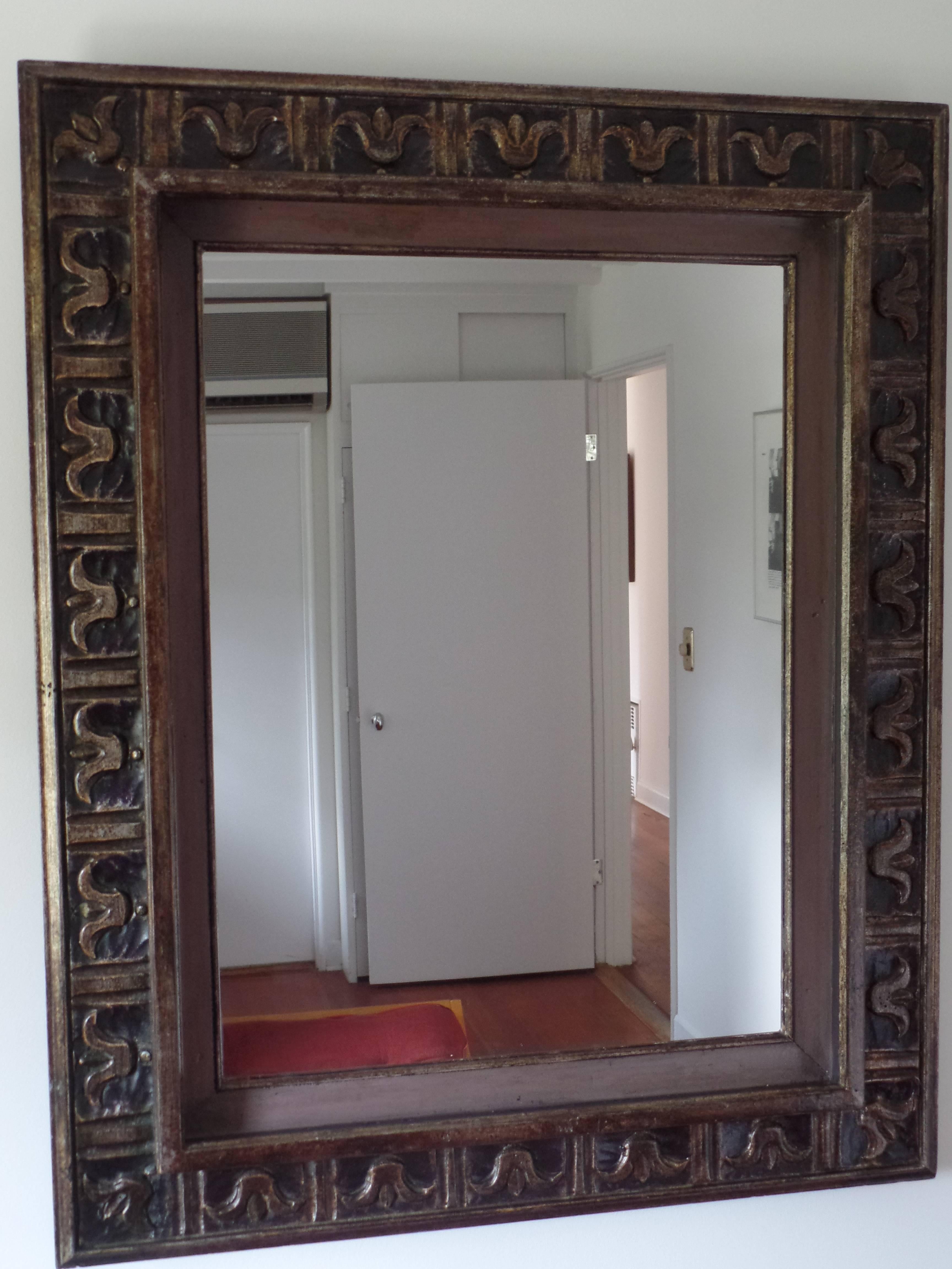 French 1940s wall mirror / frame in the modern neoclassical spirit with carved fleur d'lys motifs and Doric columns arranged sequentially around the border of the frame. The frame is highlighted with subtle silver and gold leafed details against a
