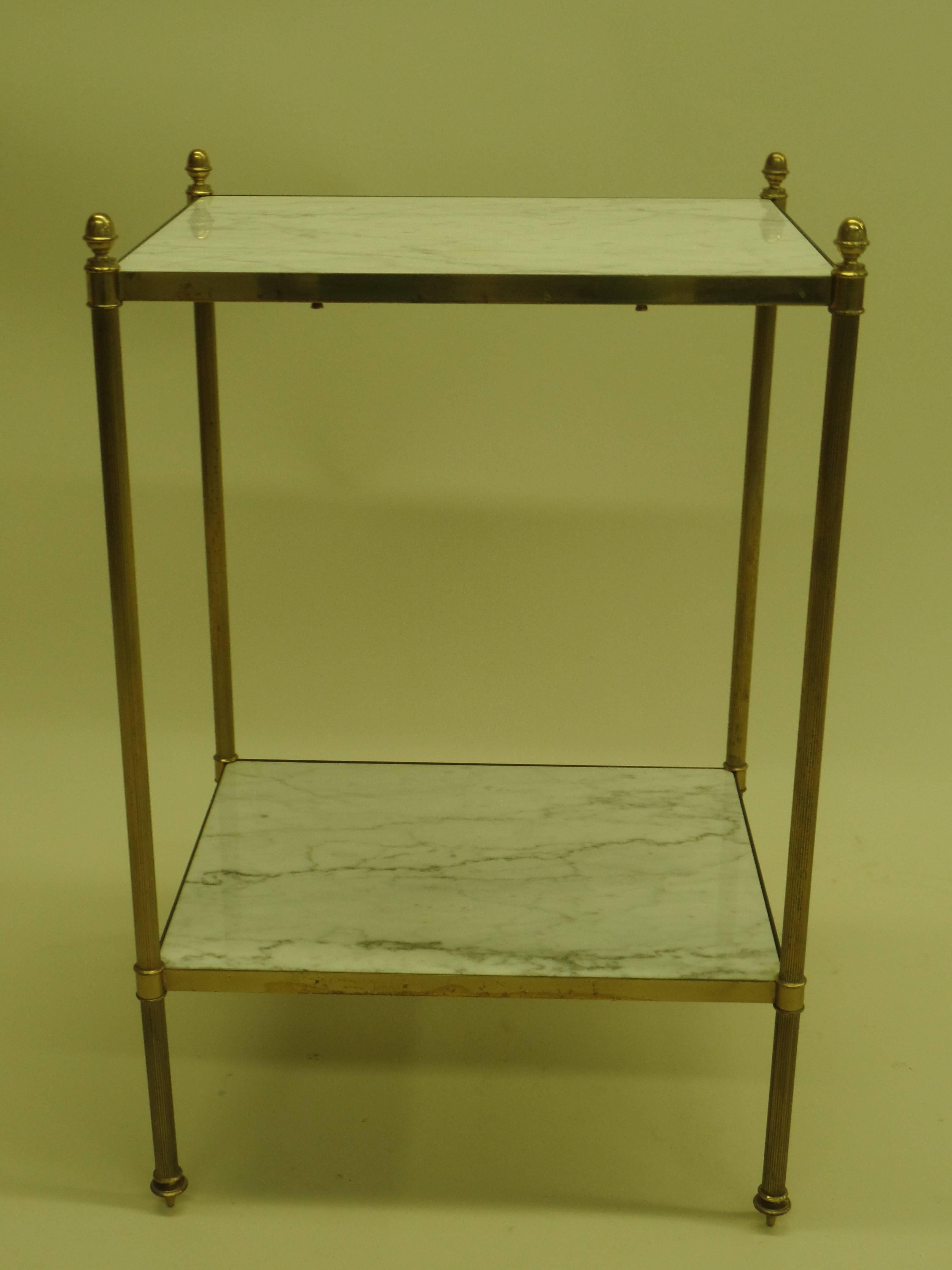 Elegant pair of French Mid-Century end tables / nightstands in the modern neoclassical style by Maison Jansen. The tables are double level, composed of solid brass frames with their original Carrara marble tops. The detailing is exquisite and