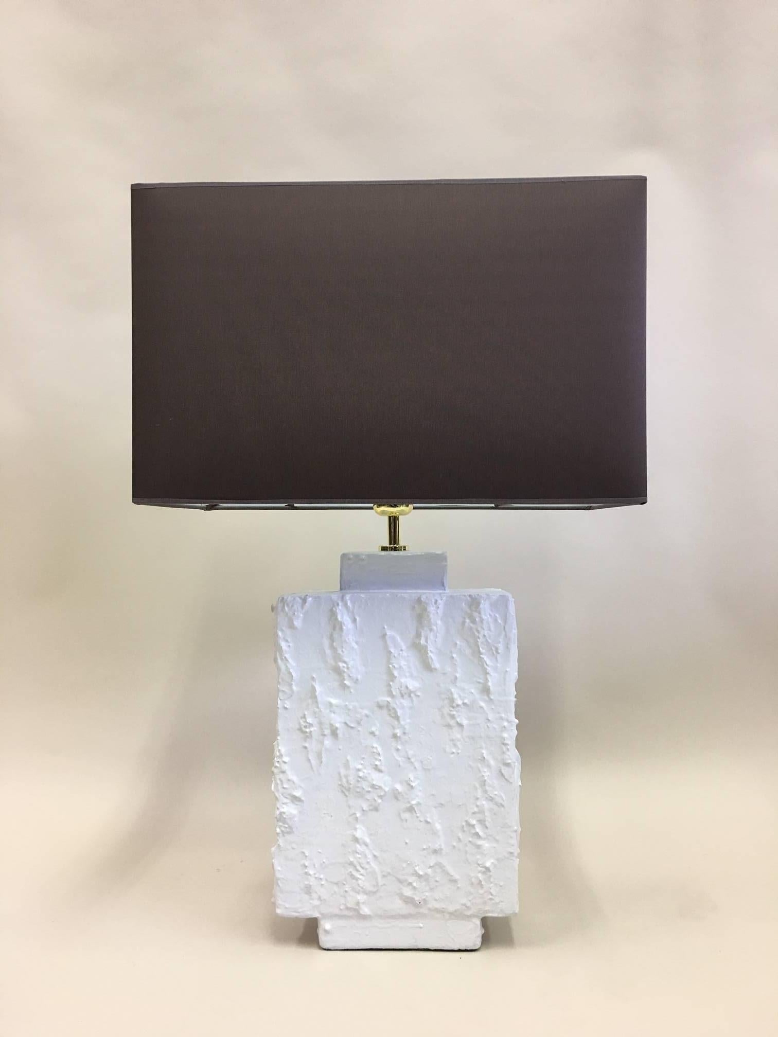 Elegant pair of French Mid-Century Modern plaster table lamps in the spirit of Alberto and Diego Giacometti. The pieces utilize rectangular geometric or architectural forms in contrast with a highly textured white plaster relief that create subtle