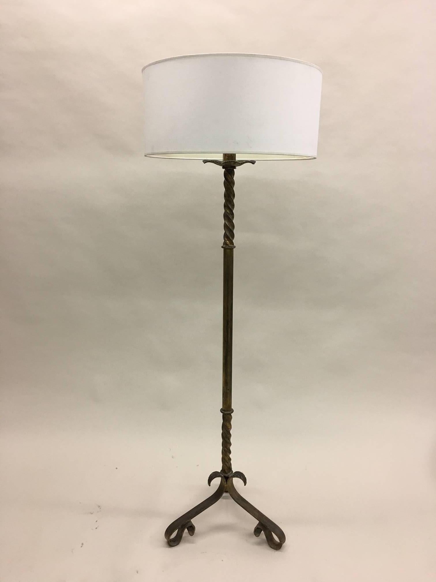 French Mid-Century hand-hammered iron standing lamp that has been hand gilt. The elegant tripod base supports a partially twisted column forming a poetic composition. 

The height of the stem is 59