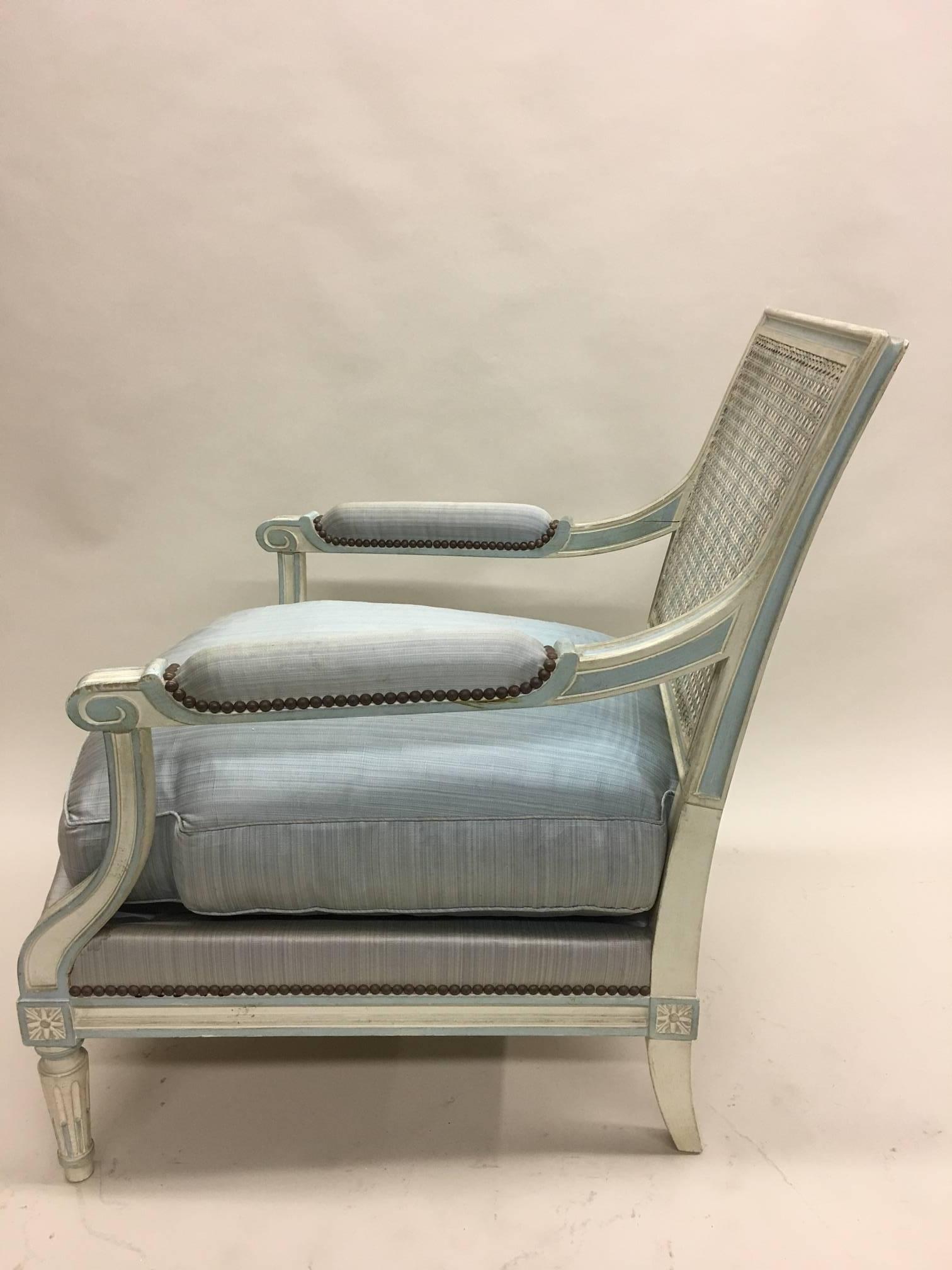 Elegant pair of Armchairs by Maison Jansen in the style of Louis XVI.

The chairs have hand carved frames and are made in similar fashion as their 18th century counterparts. The legs are fluted and tapered. The backrest is in rattan and features