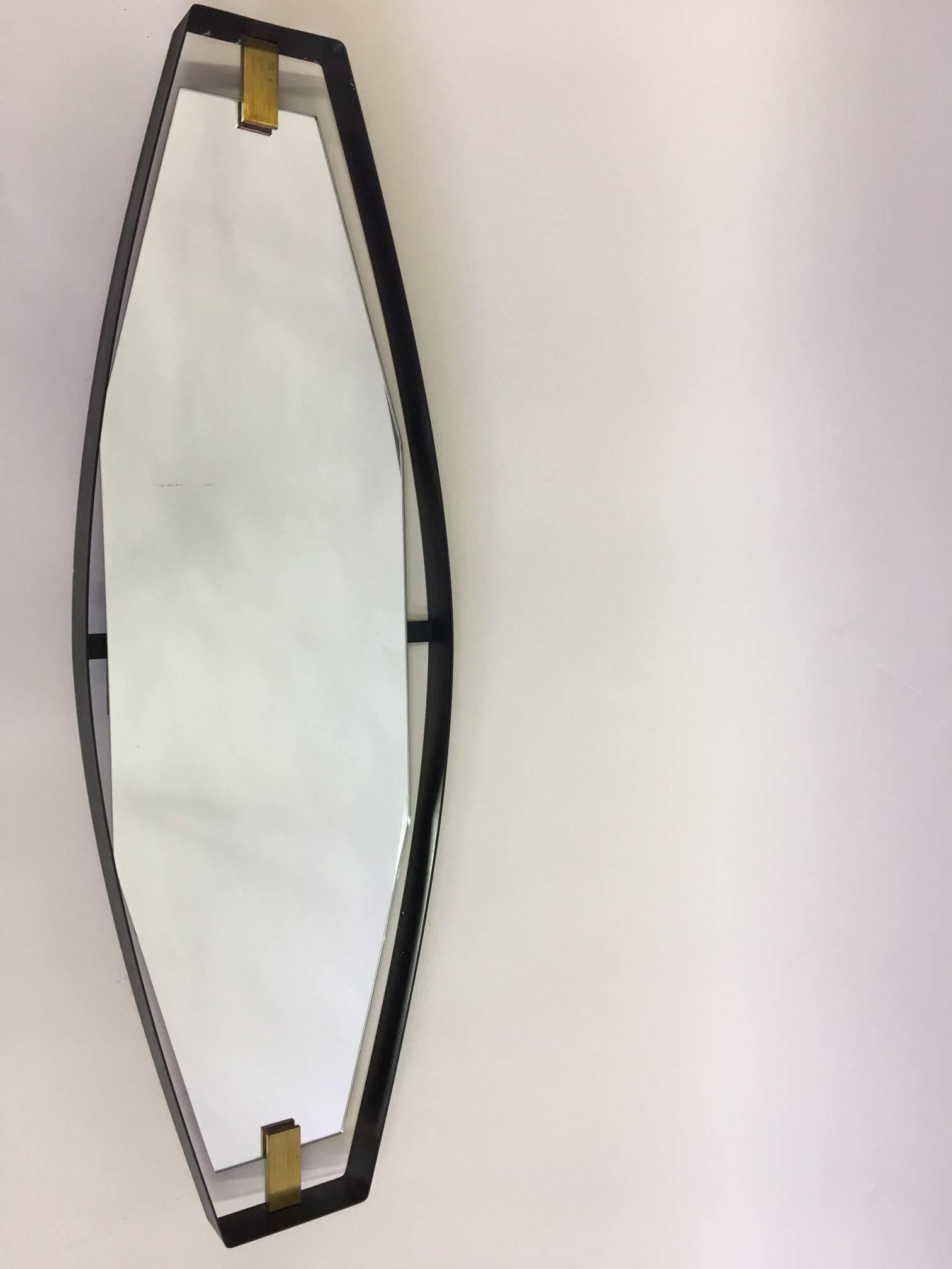 Importante specchio italiano della metà del secolo scorso dalla rara forma scultorea e inclinata, attribuito a Max Ingrand per Fontana Arte, 1950. La cornice dello specchio è costituita da una fascia di metallo smaltato nero, dalla forma semi-ovale