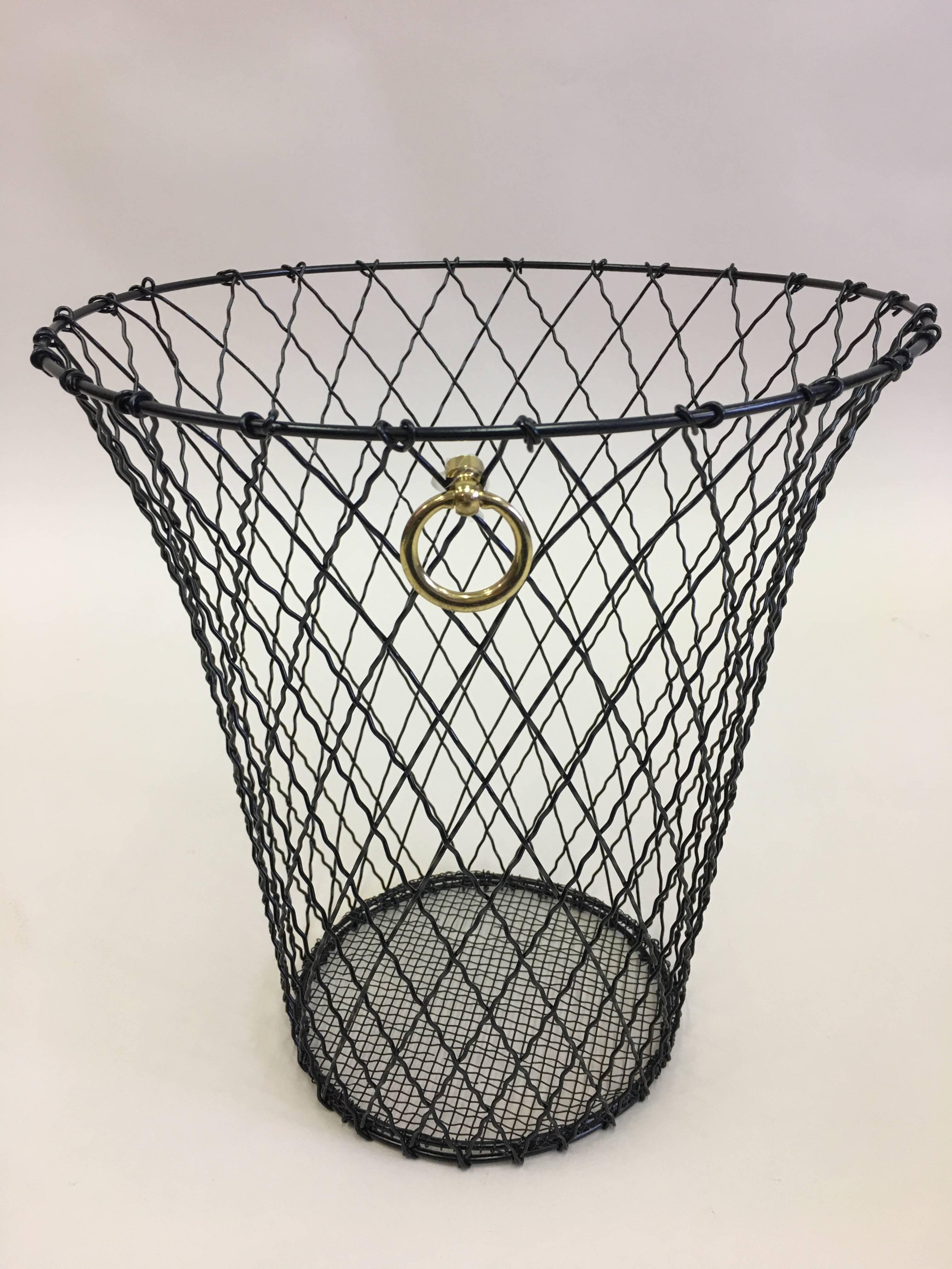 Two French trash baskets or wastebaskets that elegantly combine modern, neoclassical and industrial aesthetics. The pieces are composed of black enameled wire woven in a classic cross-hatched pattern completed by a solid brass ring pull.