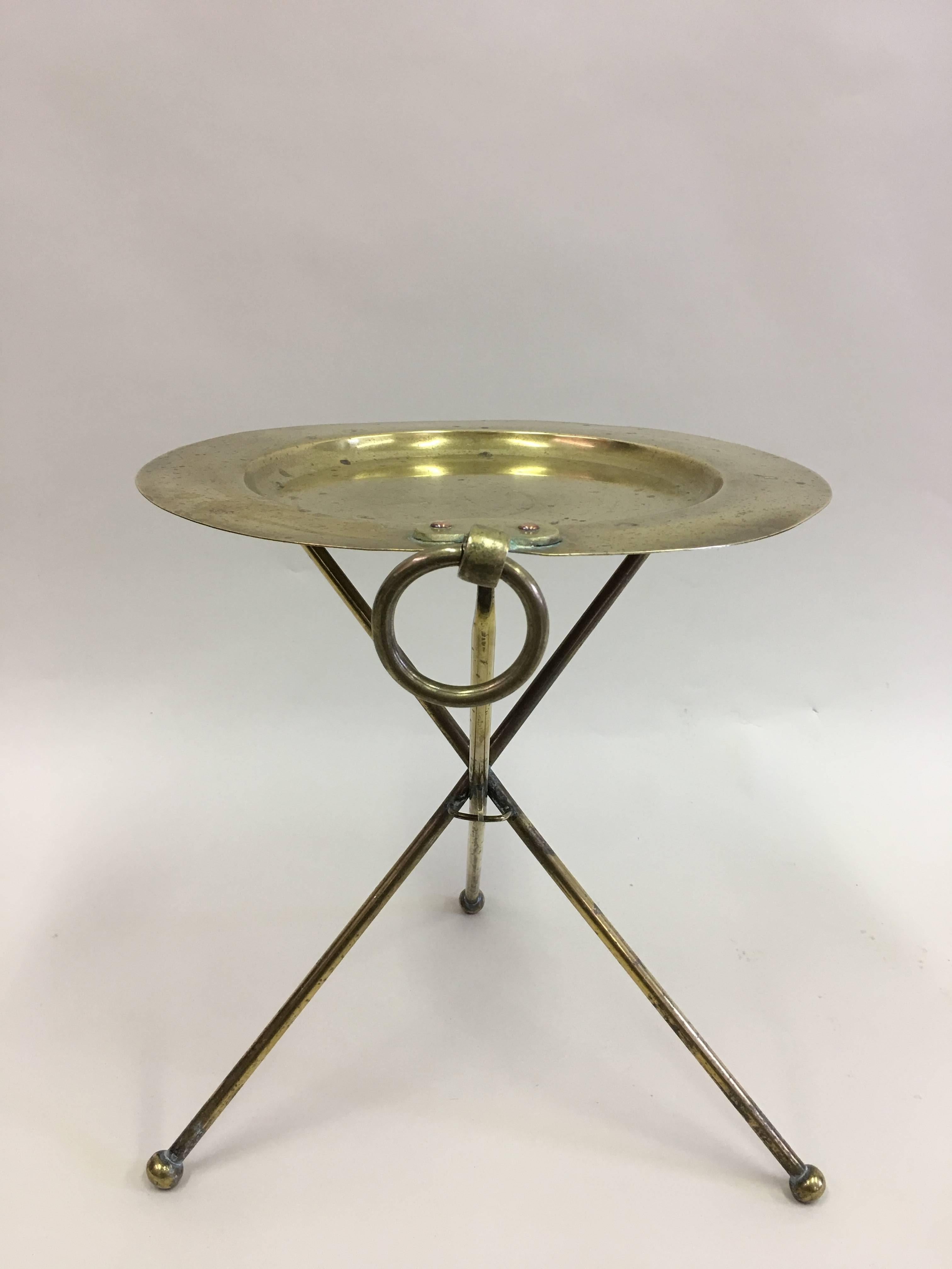 Elegant French Mid-Century solid brass guéridon, side, end or occasional table in the modern neoclassical tradition. 

The solid brass table sits on a tripod base with ball feet and supports a round top. A ring pull adorns the piece on one side.