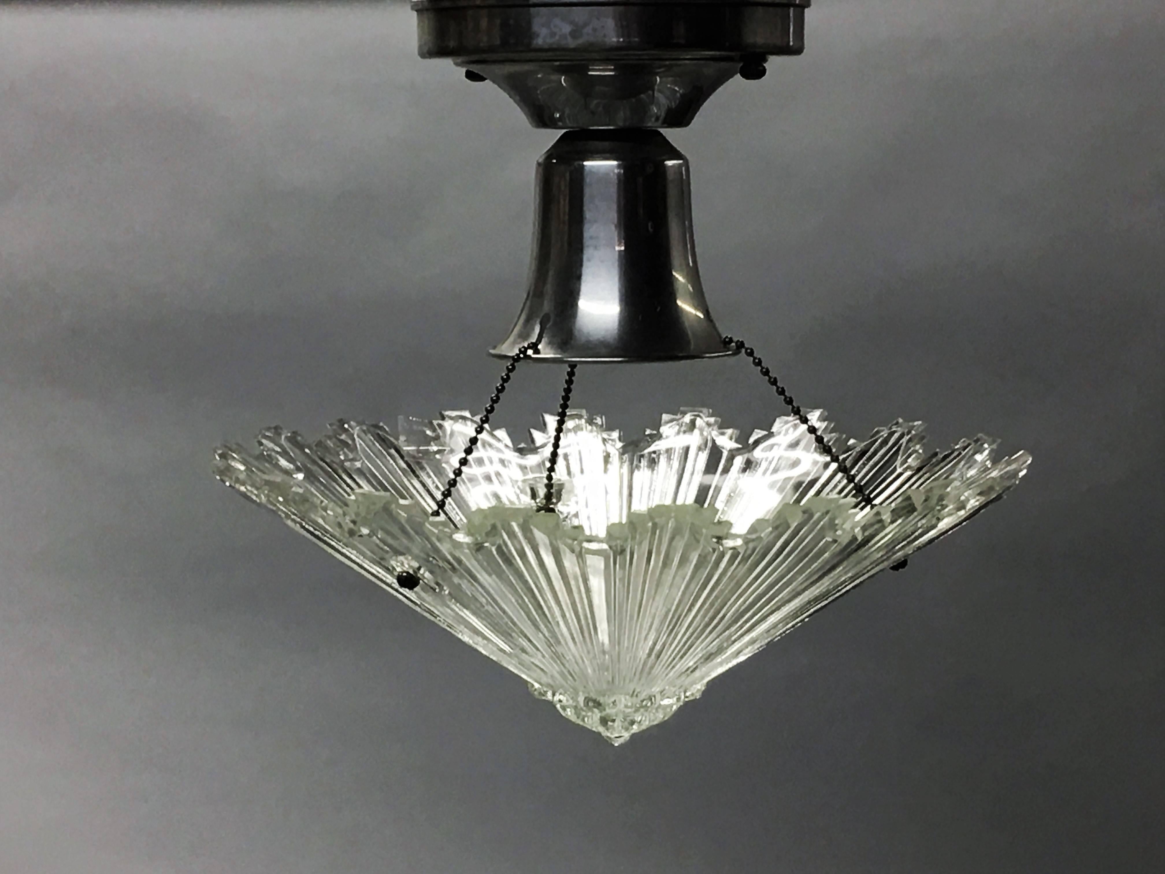 Exquisite pair of French Mid-Century Modern / Art Deco clear cut crystal sunburst fixtures / pendants attributed to Baccarat. Refined, chiseled detailing and a luminous appearance set these pieces apart.

 Height of stem is modifiable so the piece
