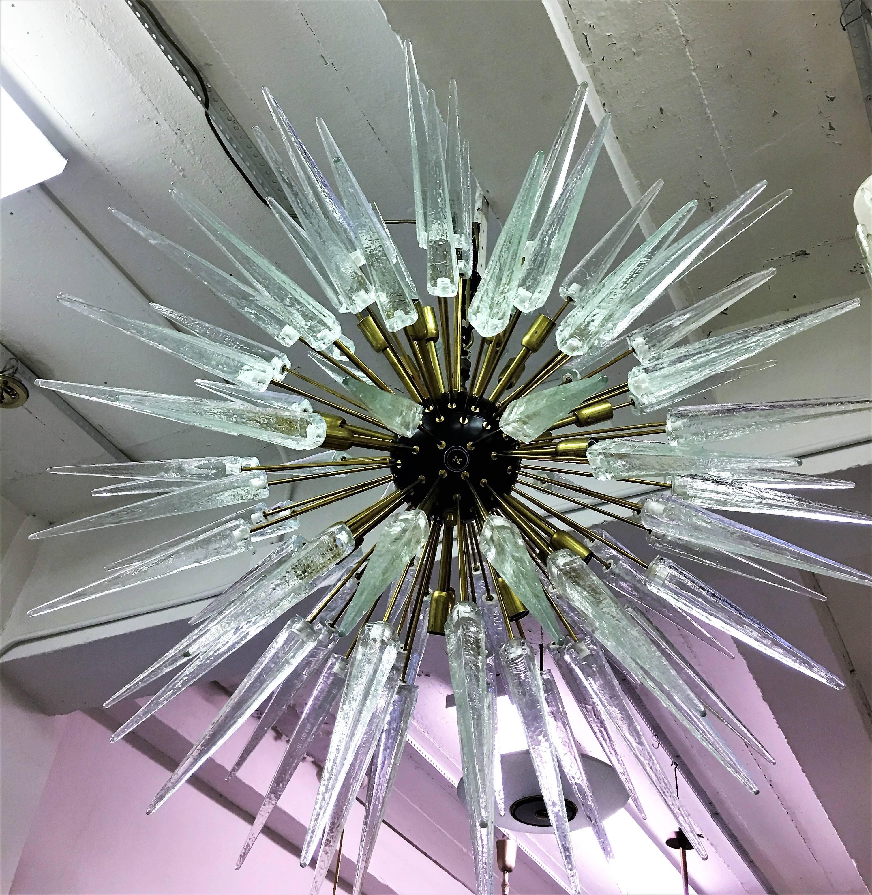 Large Round Italian Mid-Century Modern style Hand Blown Clear Murano Glass Chandelier with 99 hand blown clear Murano glass spikes to form a Sputnik. Details are in solid brass. Dimensions of chandelier alone without stem is 48” x 48”. Approximate
