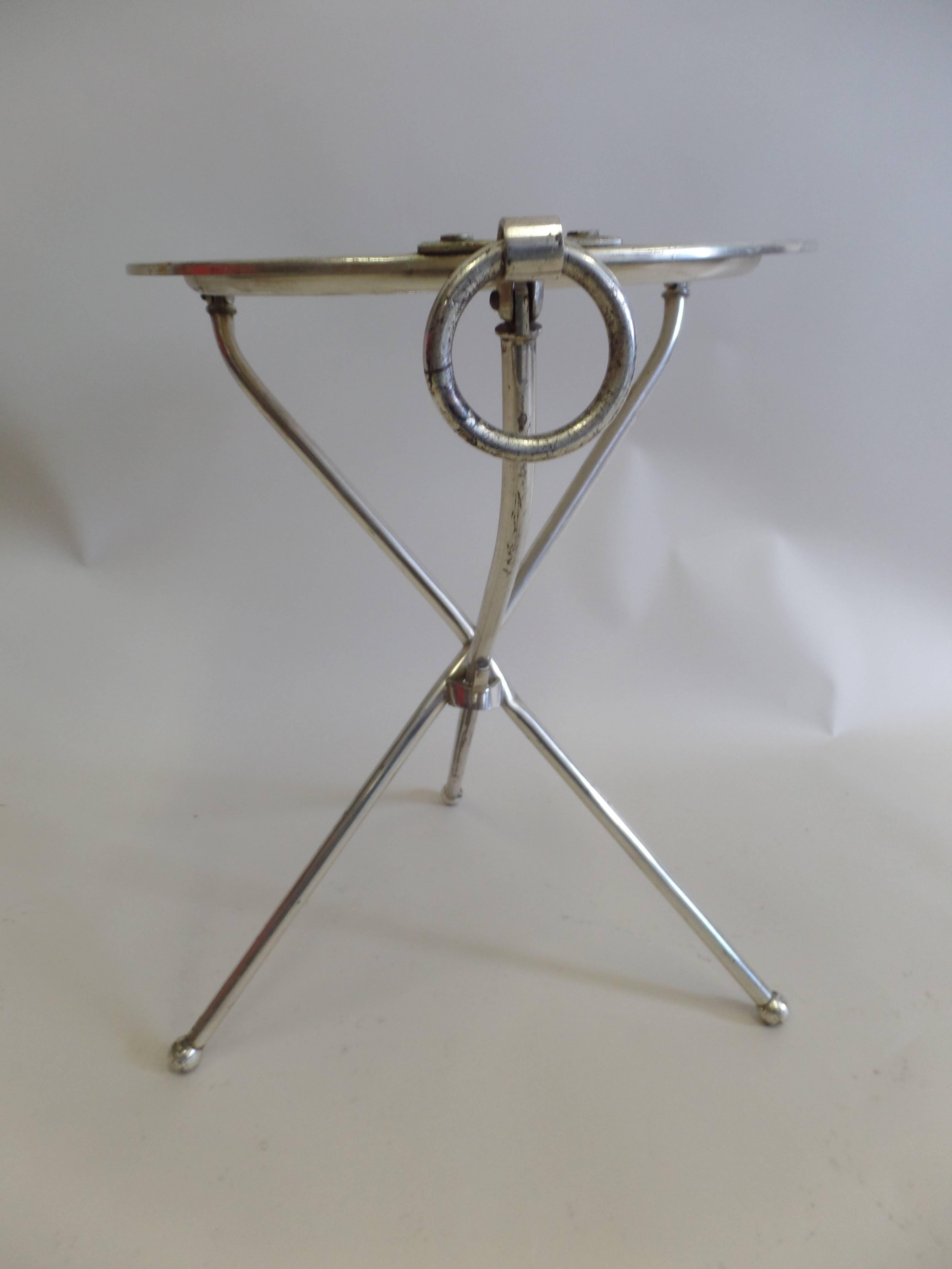 Elegant, small French Mid-Century gueridon resting on tripod legs that end in ball feet. the piece can collapses and hang on wall via its ring pull.