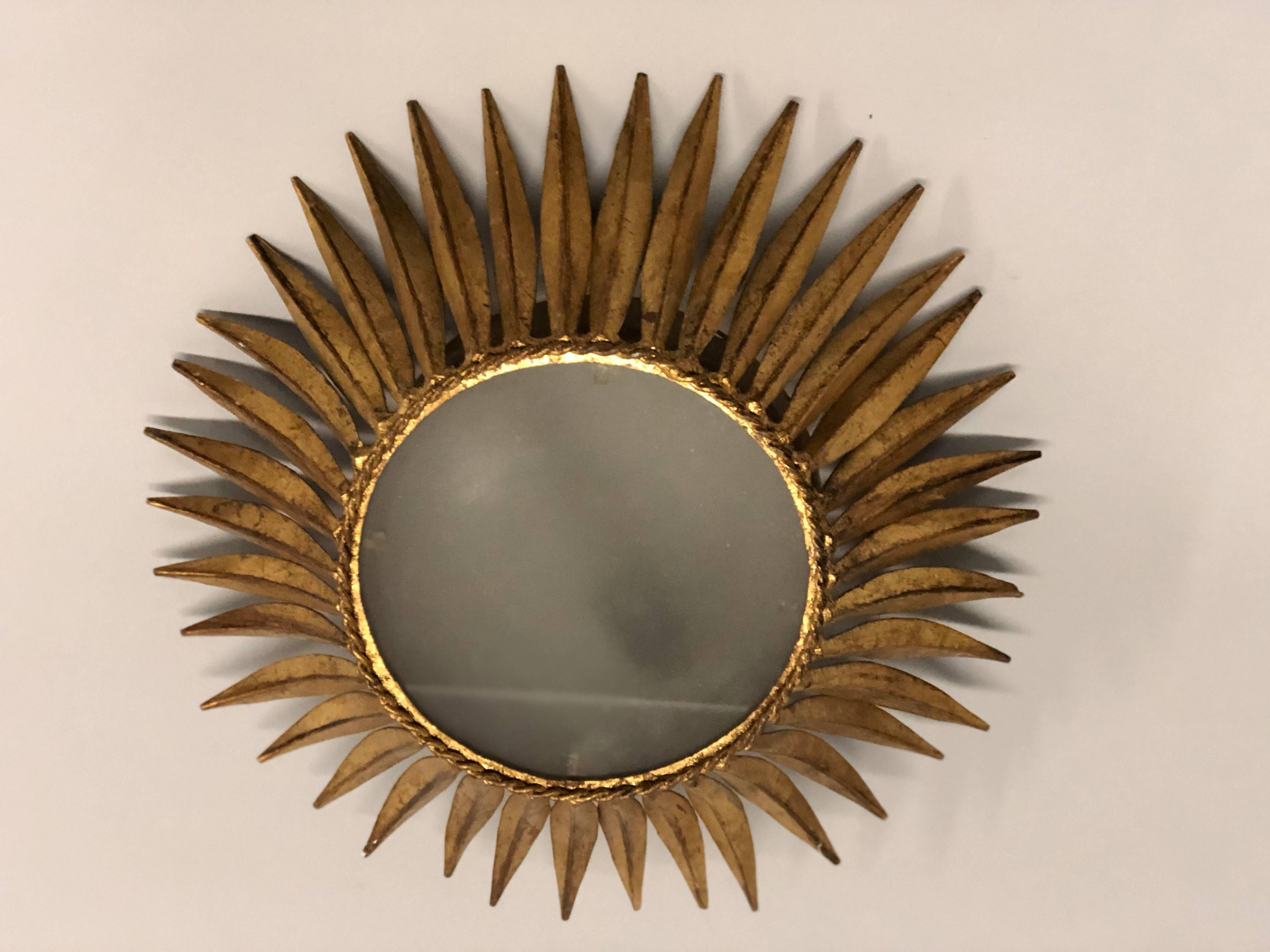 Pair of French Mid-Century Modern neoclassical style gilt iron sunburst / starburst flush mount / pendants. 

Handmade in iron and hand gilt around a central glass shade with a concentric ring of tapered leaves forming a crown or sunburst. These