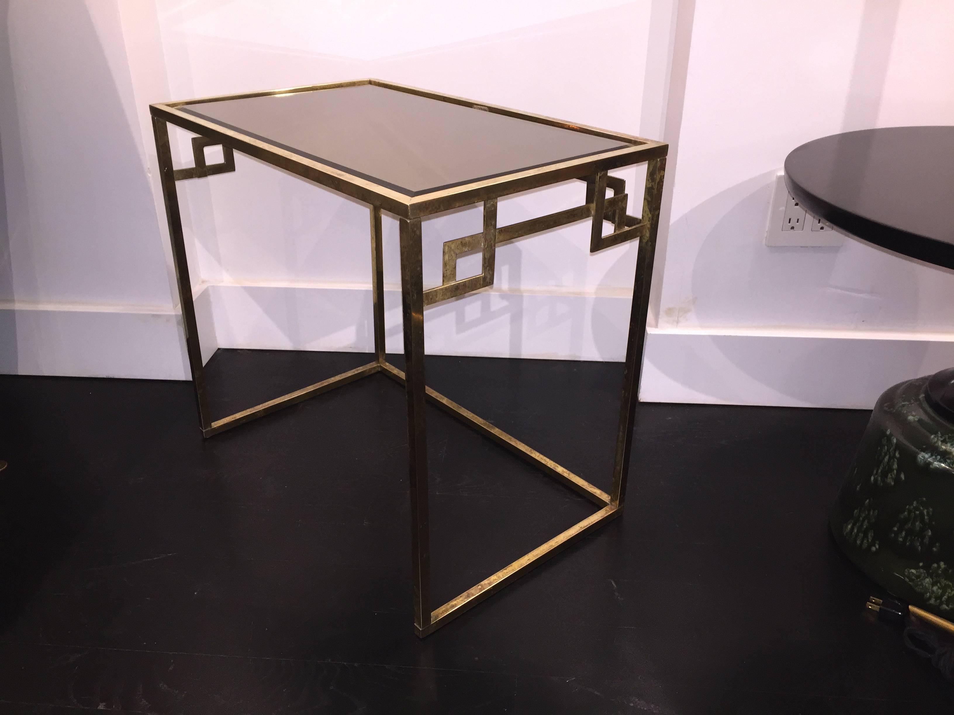 Italian brass nesting tables from the 1960s with Greek key design and original smoked glass tops. The nesting tables are kept in their original finish and glass tops have chips on some corners. Open to customization on request.