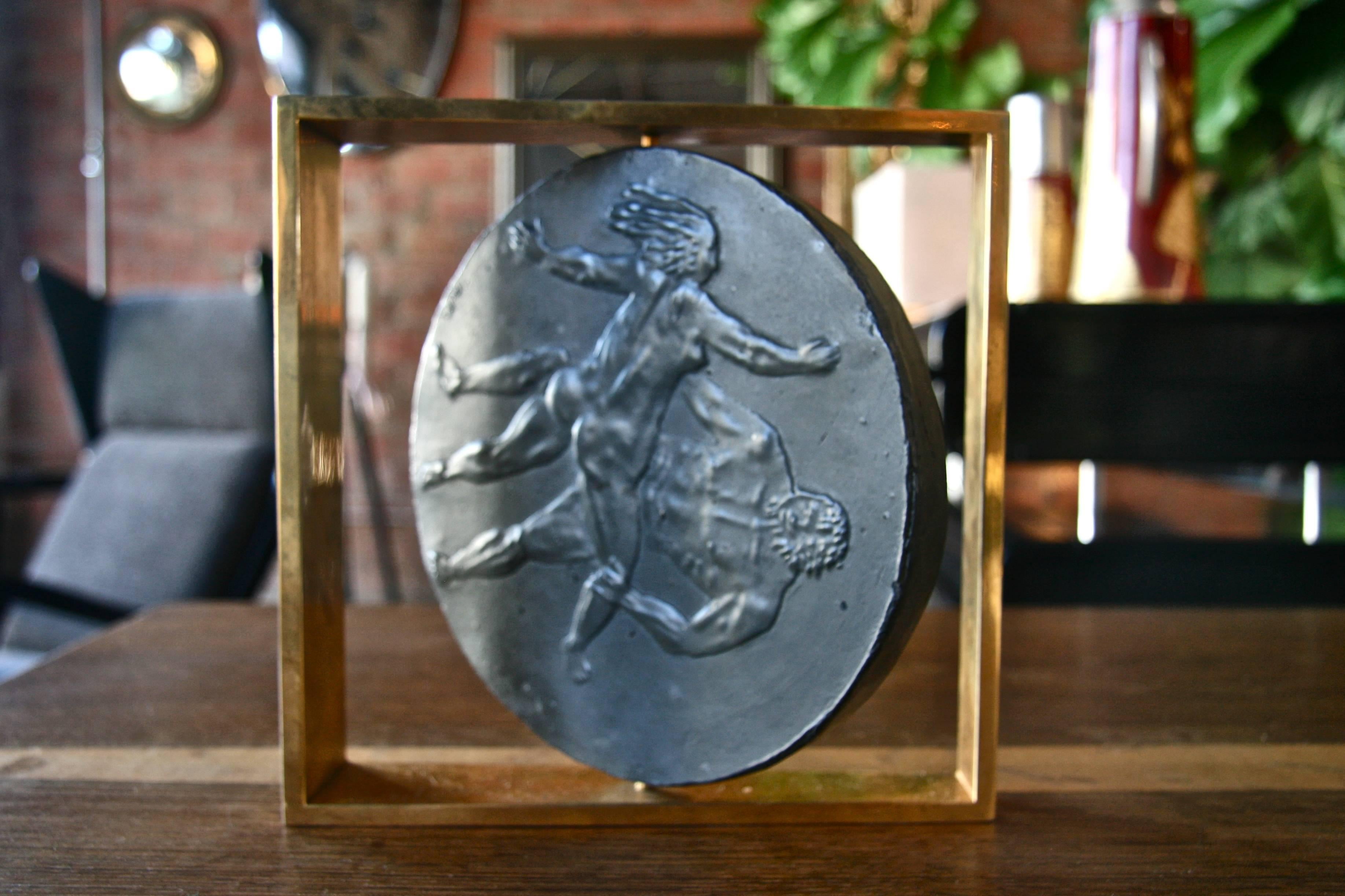 Spinning male and female etching on slate stone framed in square brass.