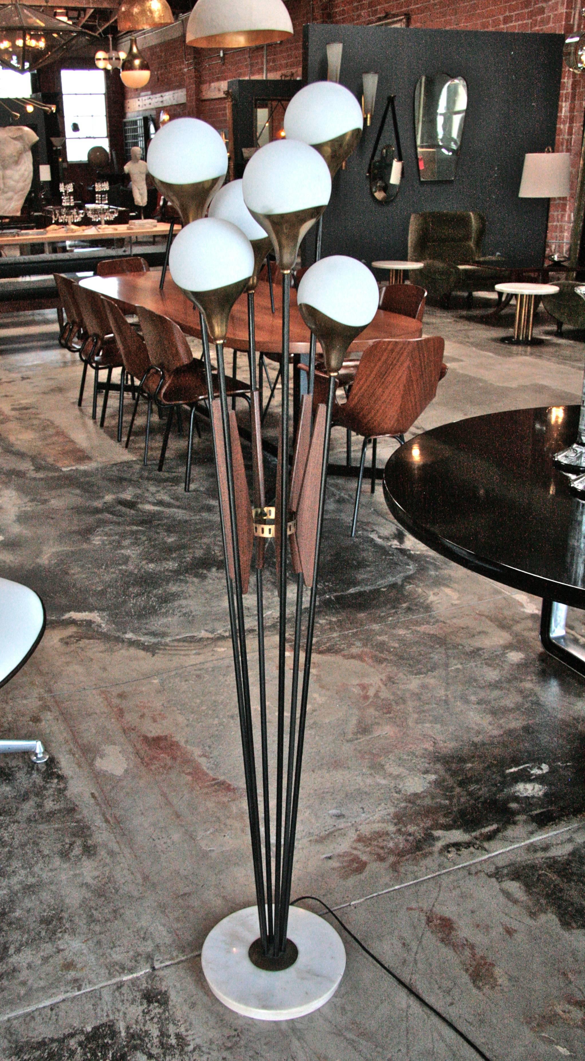 An elegant six-light floor lamp by renowned Italian production company Stilnovo. A rare model with curved brass cups holding six opaque glass diffuser with brass finial tops.