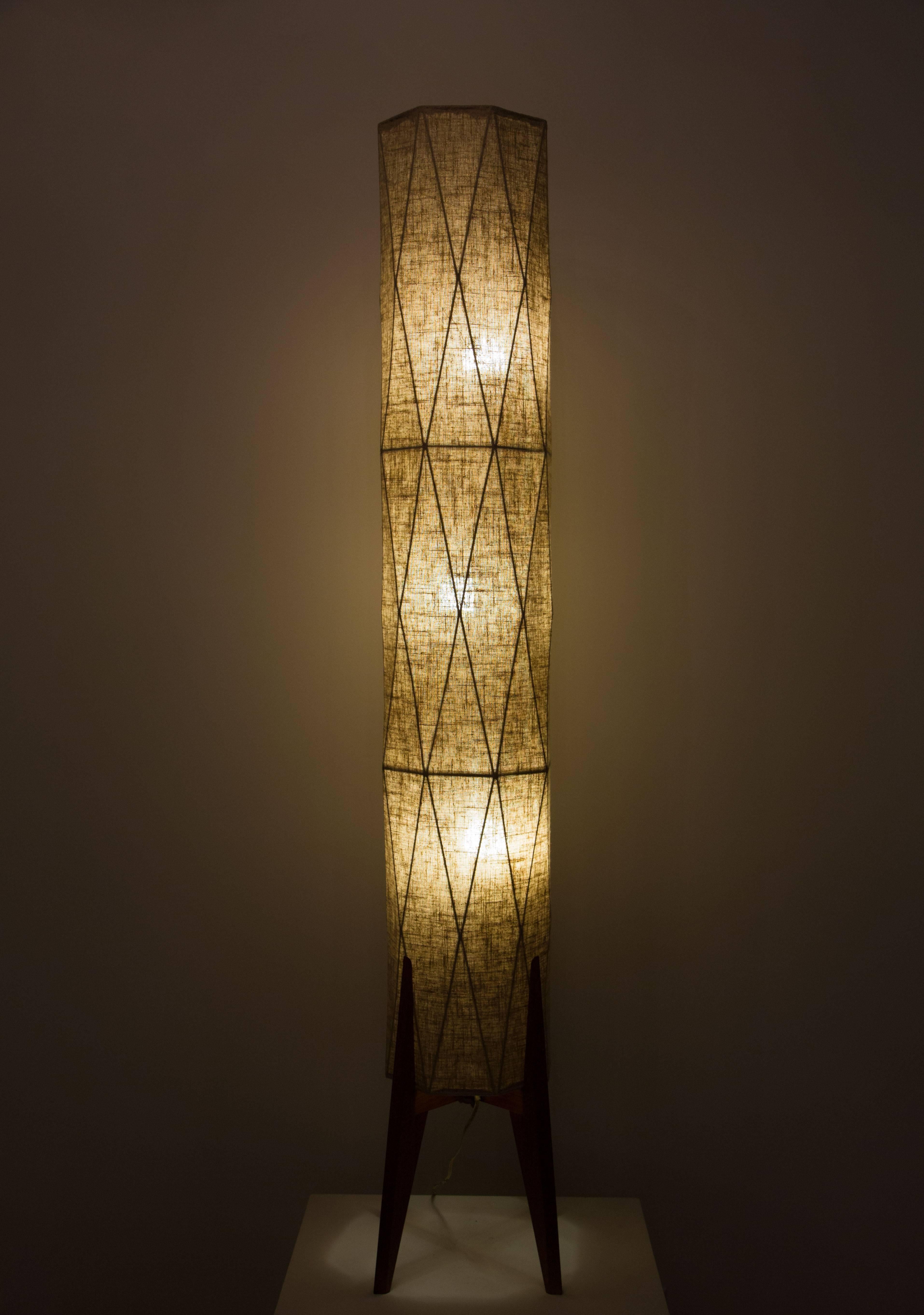 A tall standing floor lamp with teak legs with faceted linen shade.