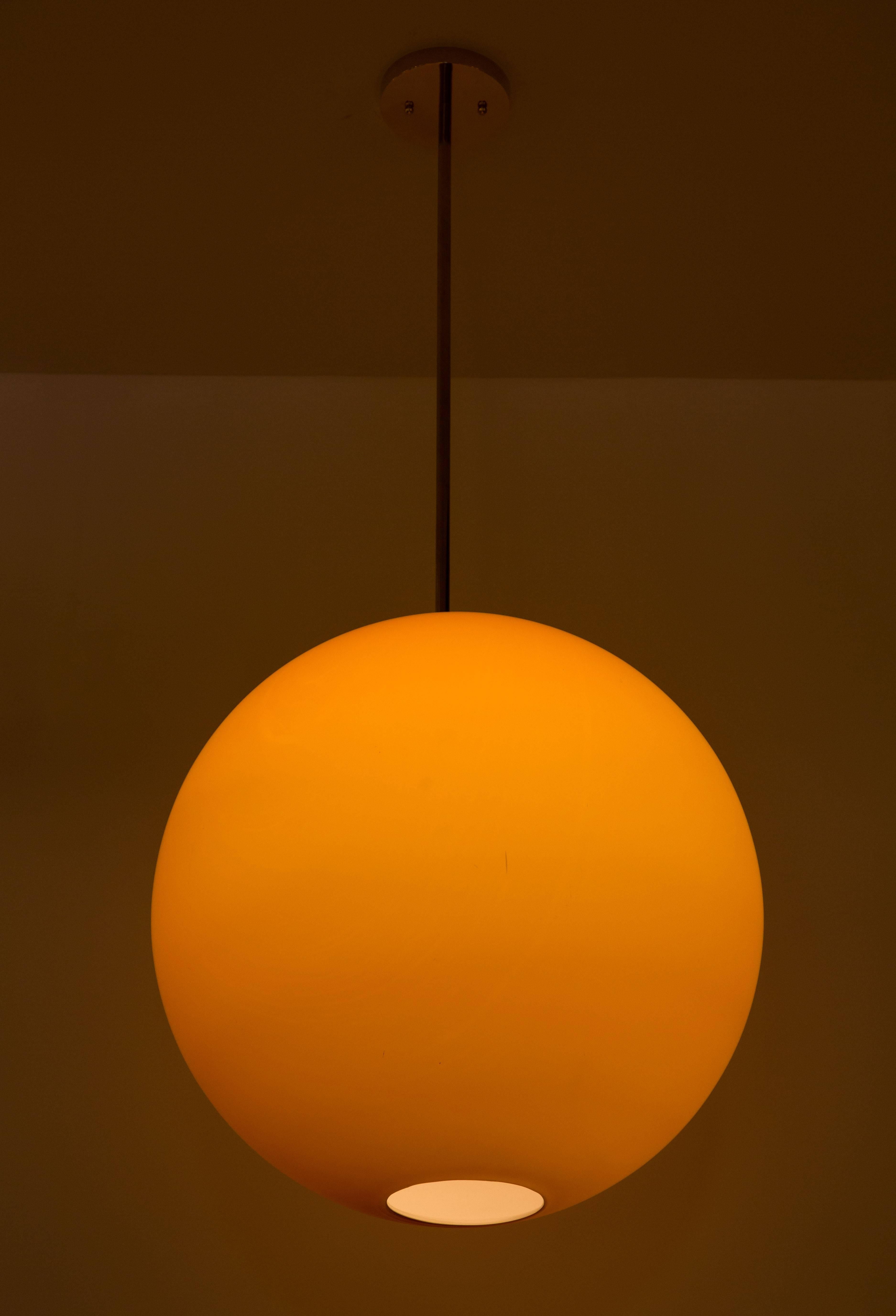 A large cased glass sun globe in deep orange with brass stem and 
canopy. Lampage is one E26 ceramic socket for up to 100 watts.