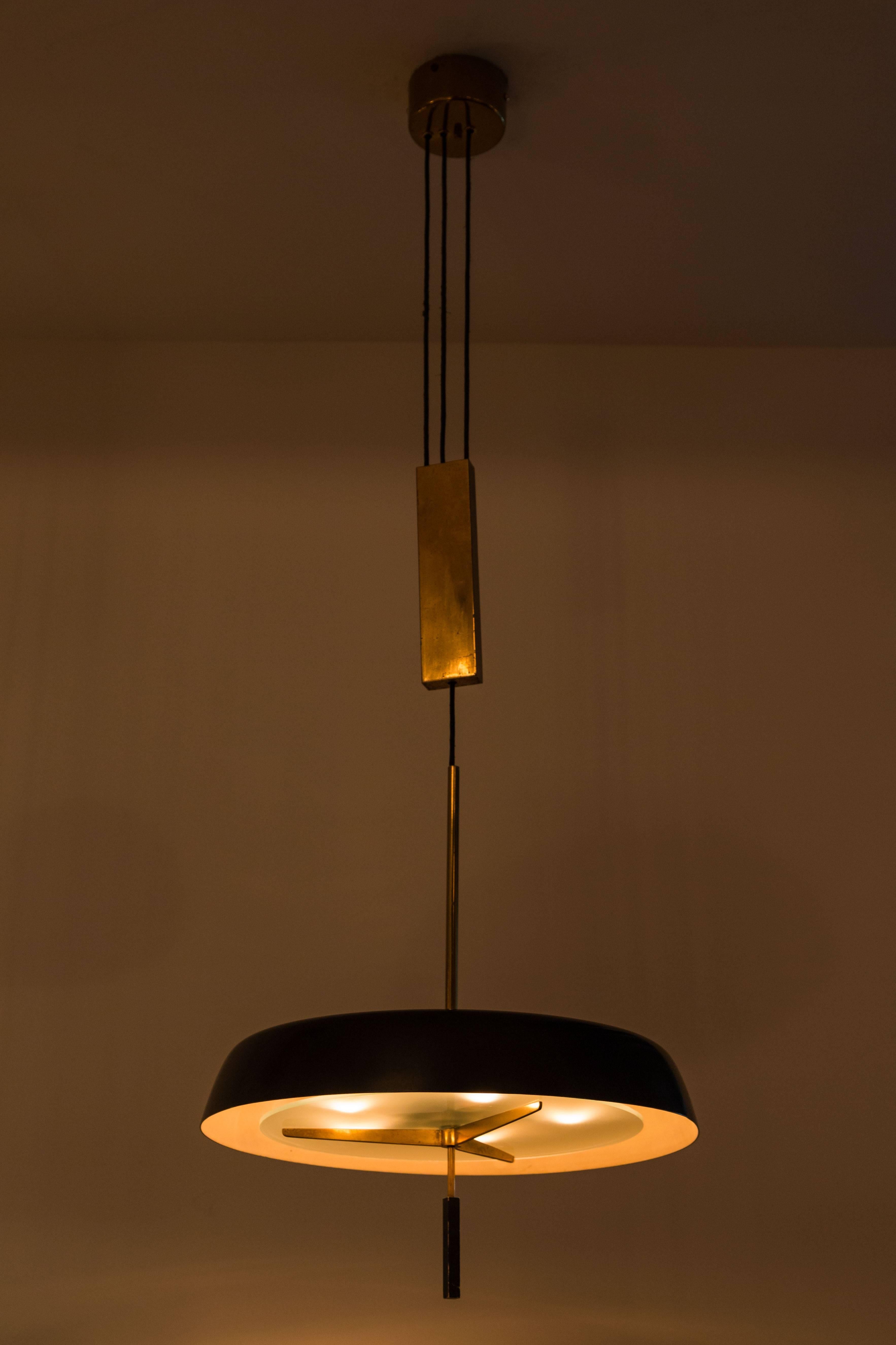 Pendant light with brass pulley by Stilnovo. Black lacquered aluminum, solid brass pulley and hardware with frosted glass diffuser. Perforations to top of shade. Made in Milan, 1960s. Five E27 40w maximum bulbs. Overall drop can be customized

 