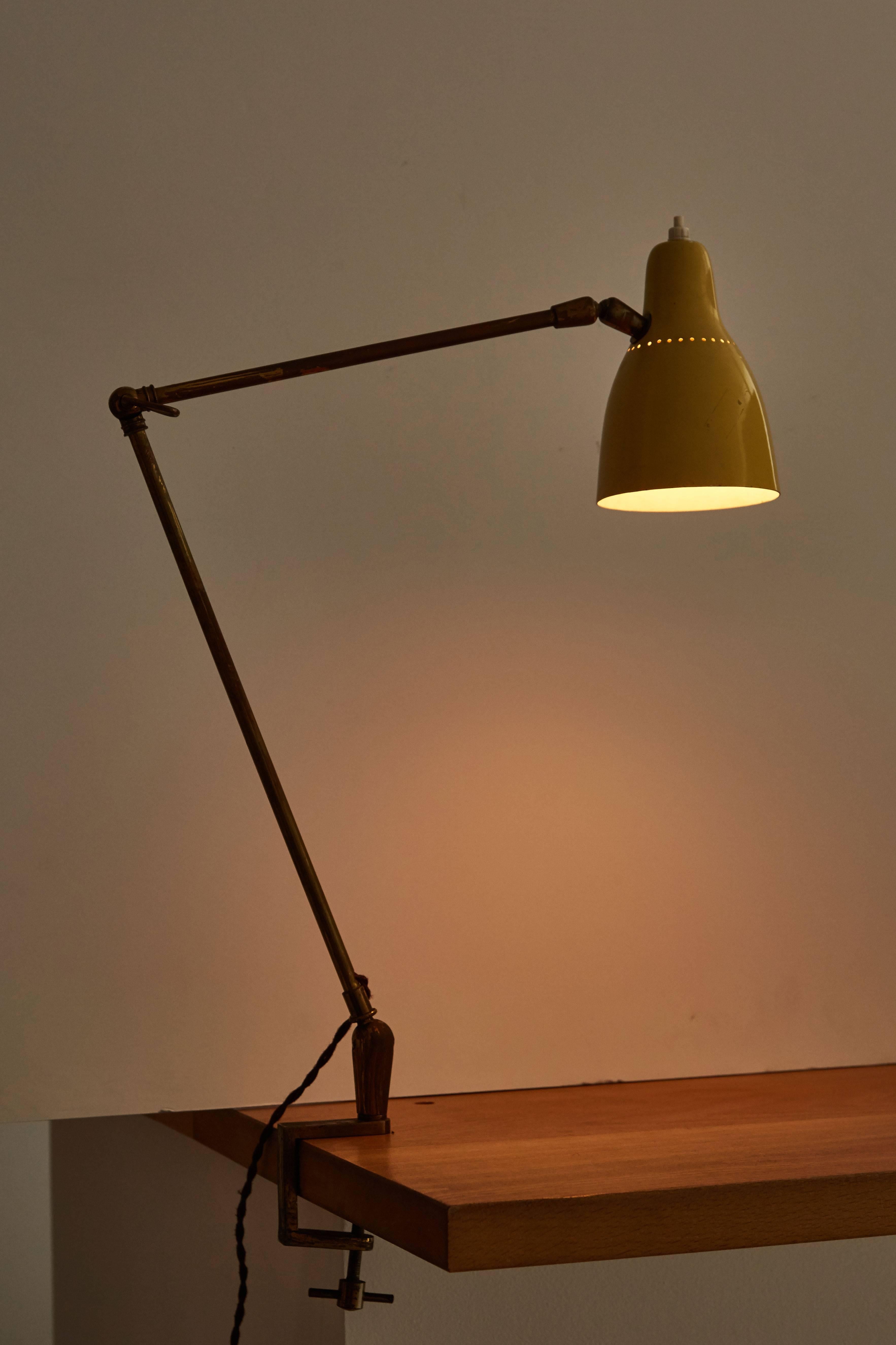 Table mounted articulating task lamp made by O-Luce in the 1950s. Perforated shade articulates up/down from the ball joint. Arm extends in height with brass key. Rewired with French twist silk cord. Takes an E27 60w maximum bulb.