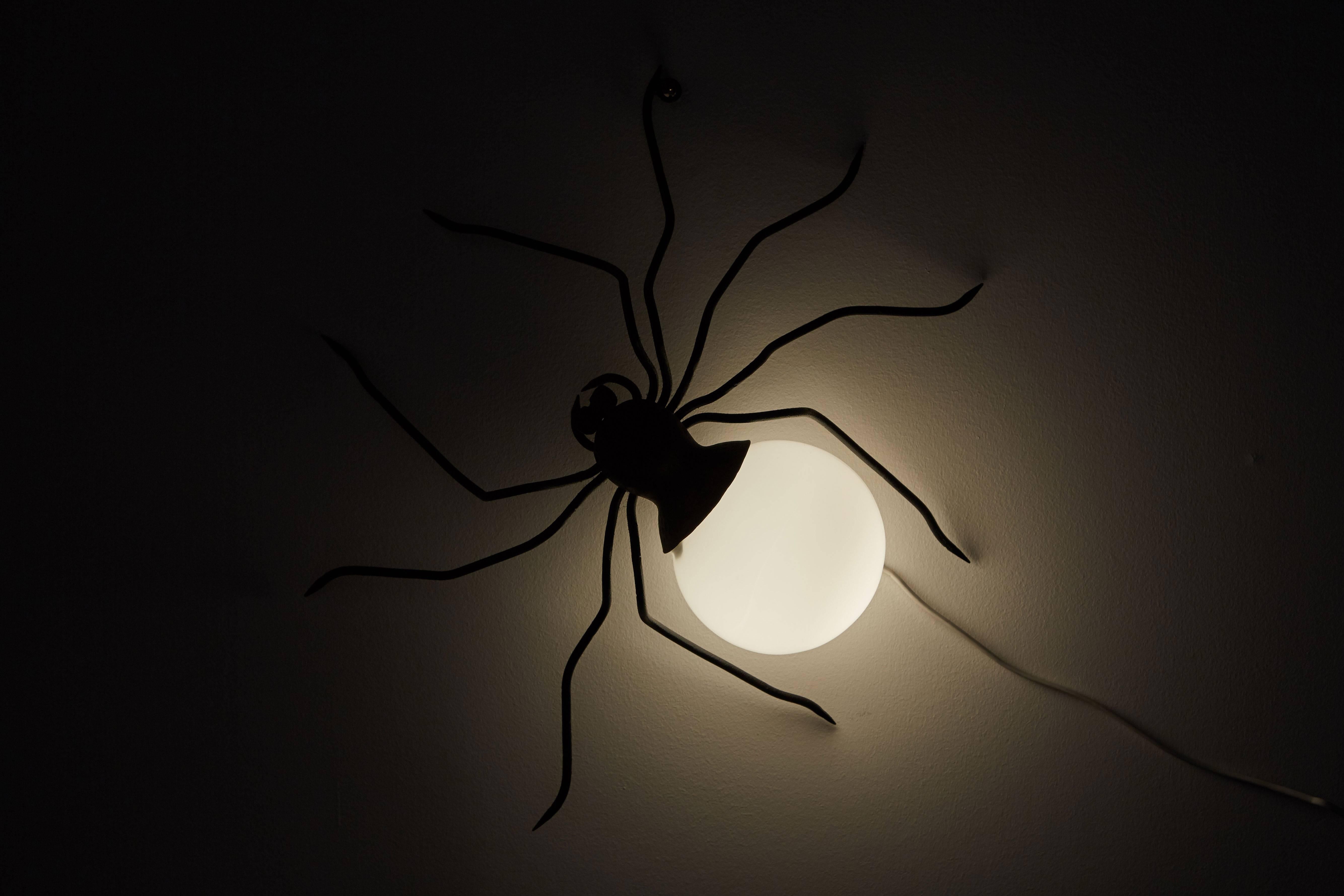 Spider wall light designed in Italy, circa 1950s. Patinated brass hardware and white glass globe. Wired for US junction boxes. Takes one E27 75 W maximum bulb.