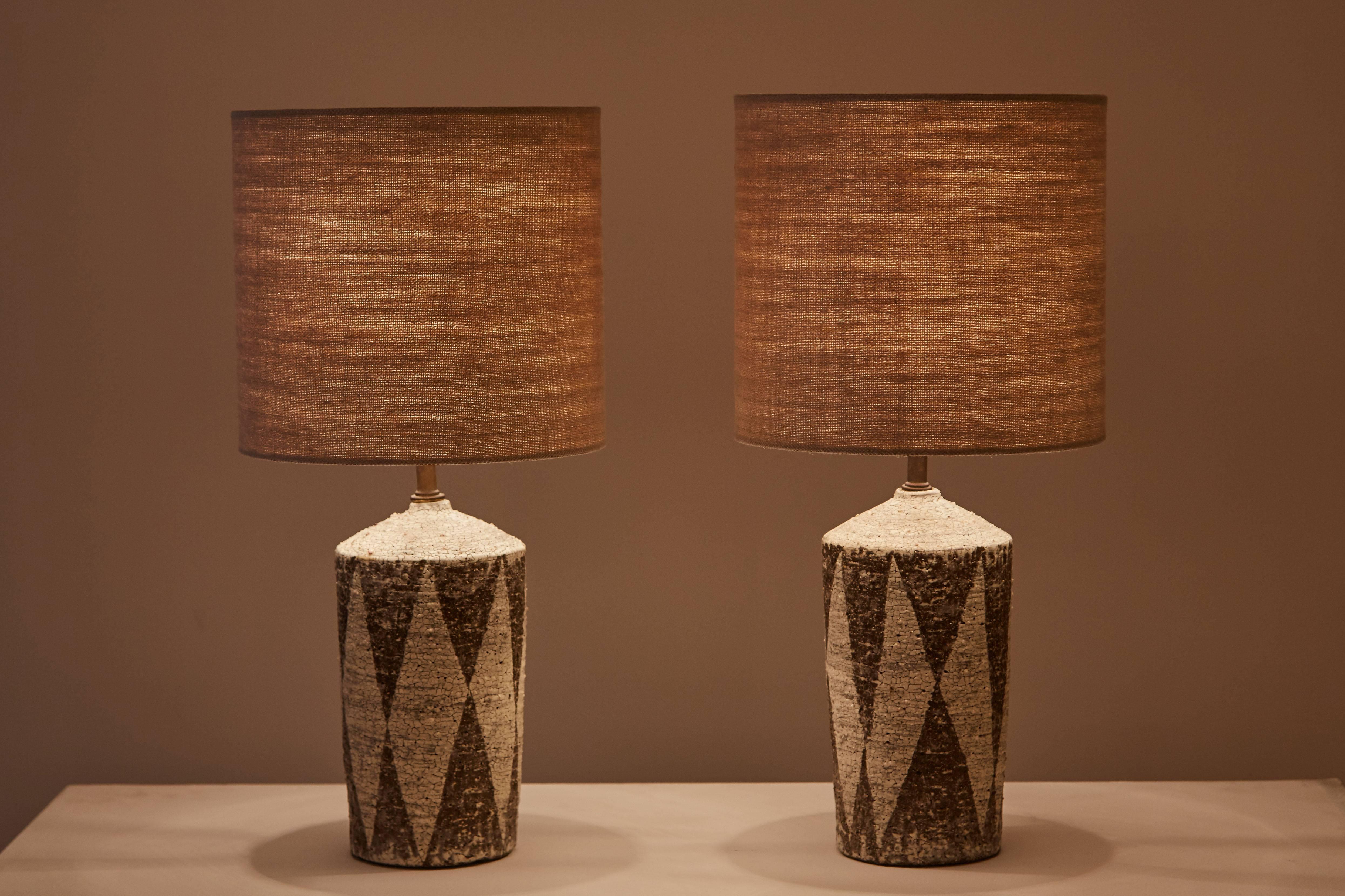 Pair of studio ceramic table lamps, hand glazed with custom linen shades. Made in the USA and signed on the bottom by artist. Original cord. Each lamp takes an E26 75w maximum bulb.