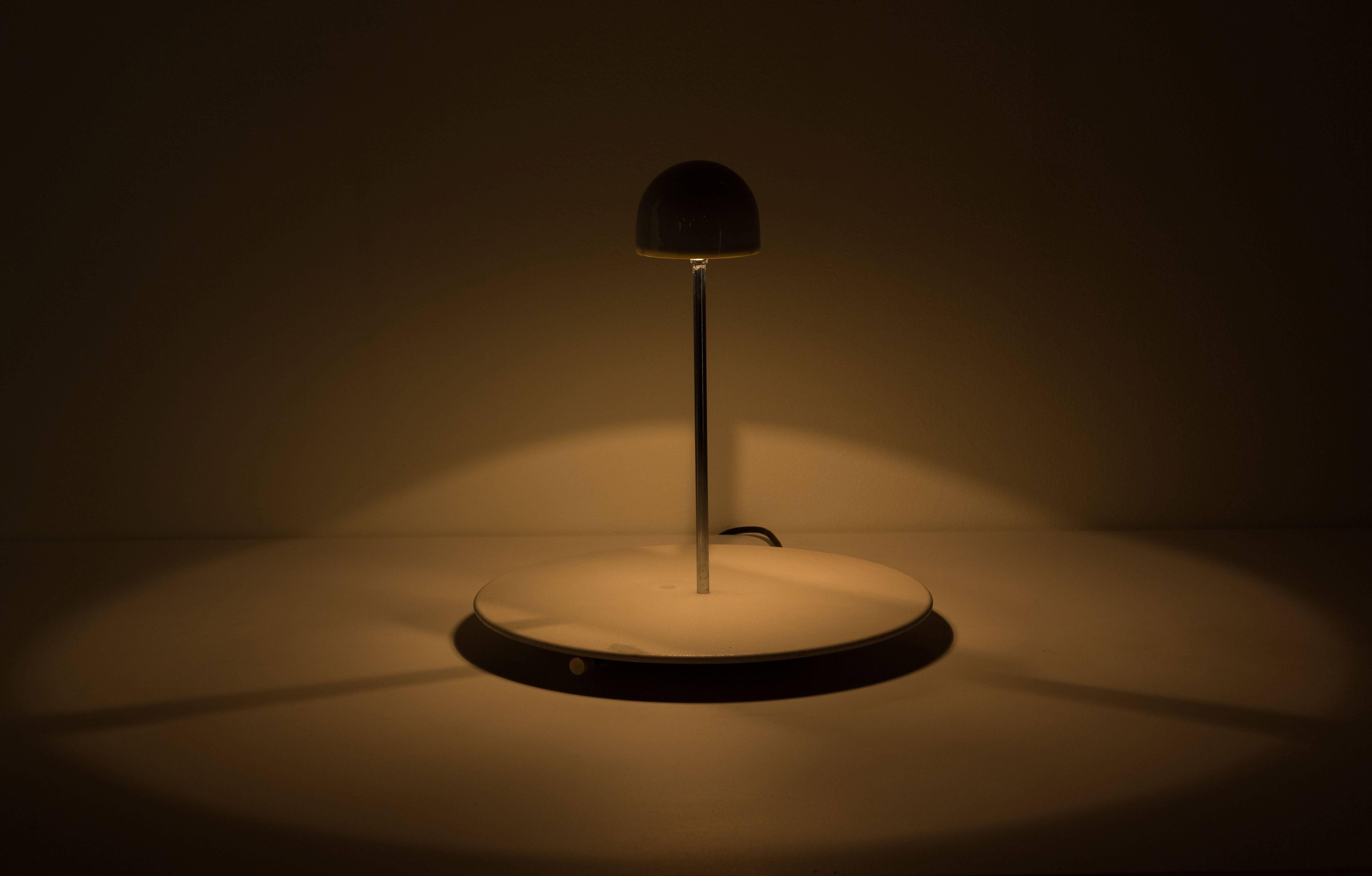 Nemea table lamp designed by Vico Magistretti for Artemide in 1979. Painted metal base acts as a diffuser for down light. Chrome metal stem and porcelain shade. Original cord. Takes one G9 halogen bulb.
