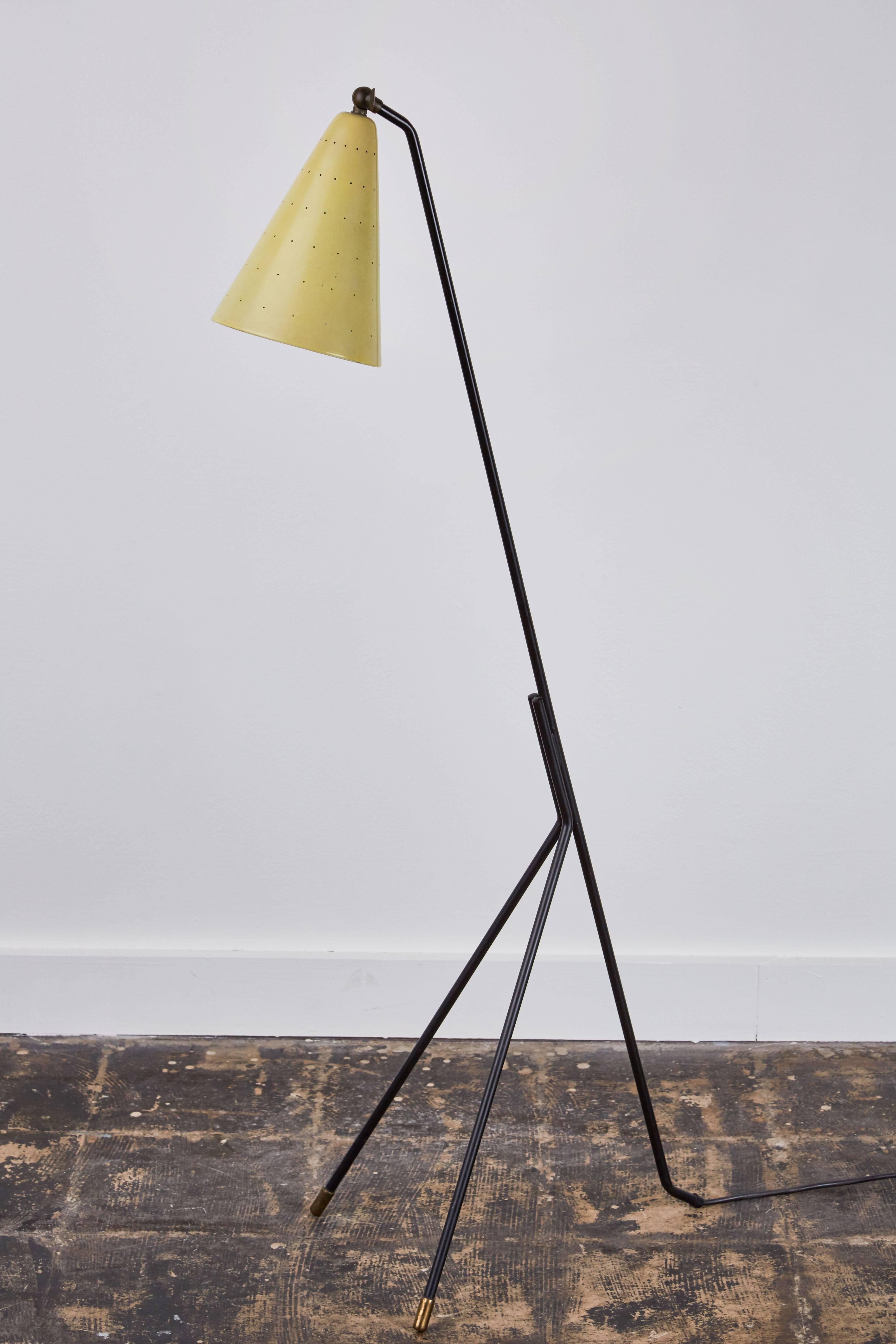 Floor lamp designed by Svend Aage Holm Sorensen. Designed in Copenhagen, circa 1950s. Black lacquered tripod base, front legs with brass leg ends, original lacquered shade mounted with switch, shade decorated with small perforations. Original cord.
